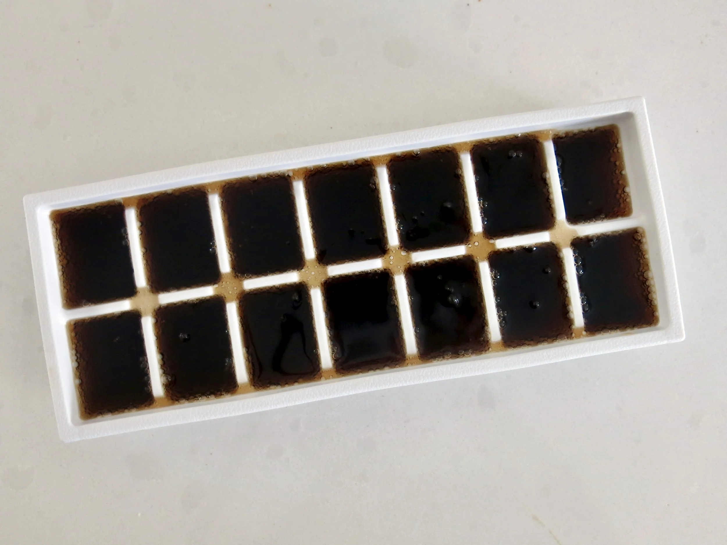 An ice cube tray filled with cola.
