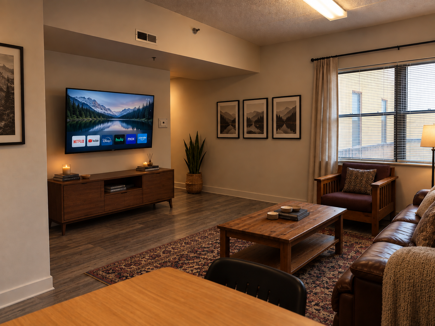 Furnished living room at Lattimore Hall with leather sofa, wall-mounted TV, and dining table