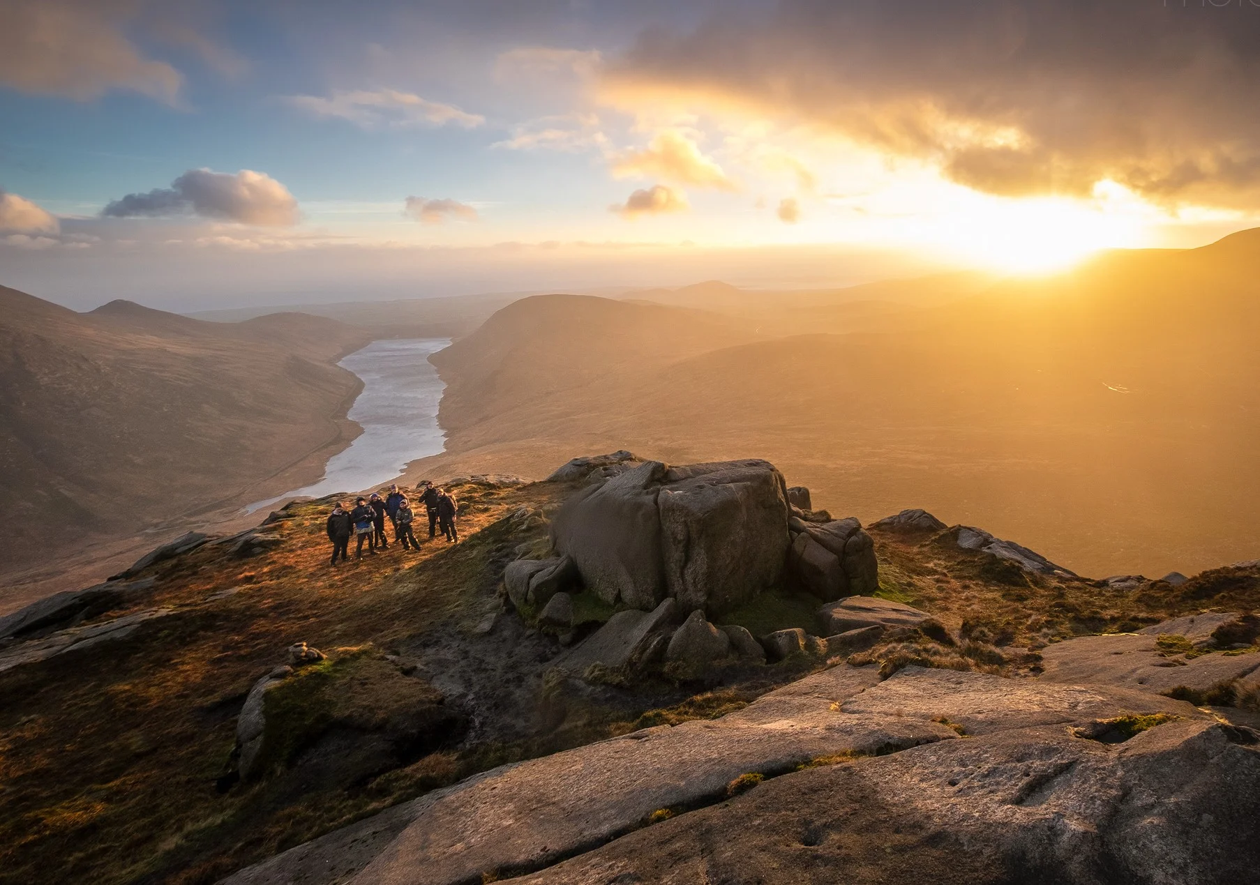 A workshop group experience a stunning sunset on the summit of Doan in the Mourne mountains
