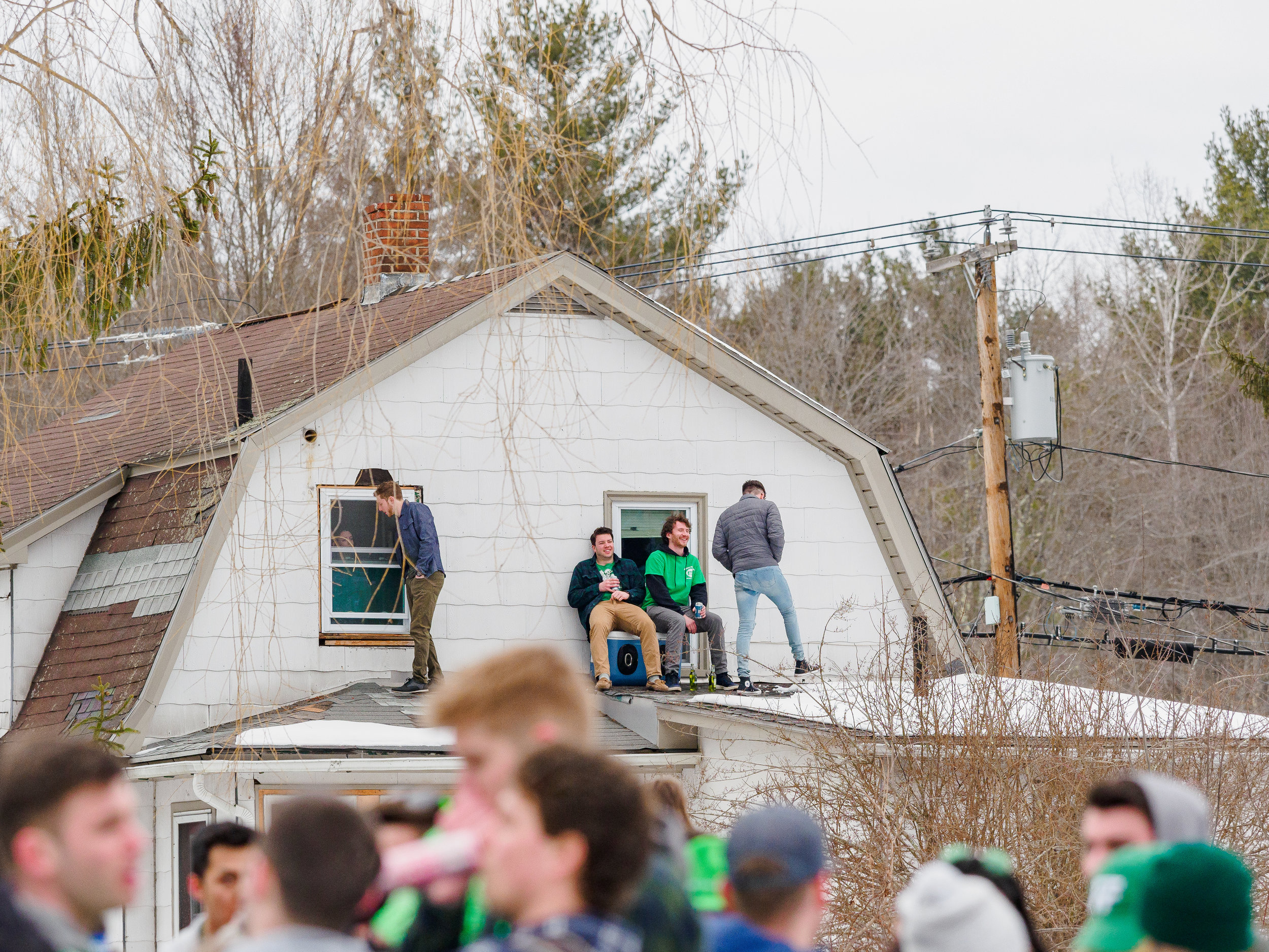  Party-goers watch from the roof of a house as large crowds gather outside in South Amherst during Blarney.  