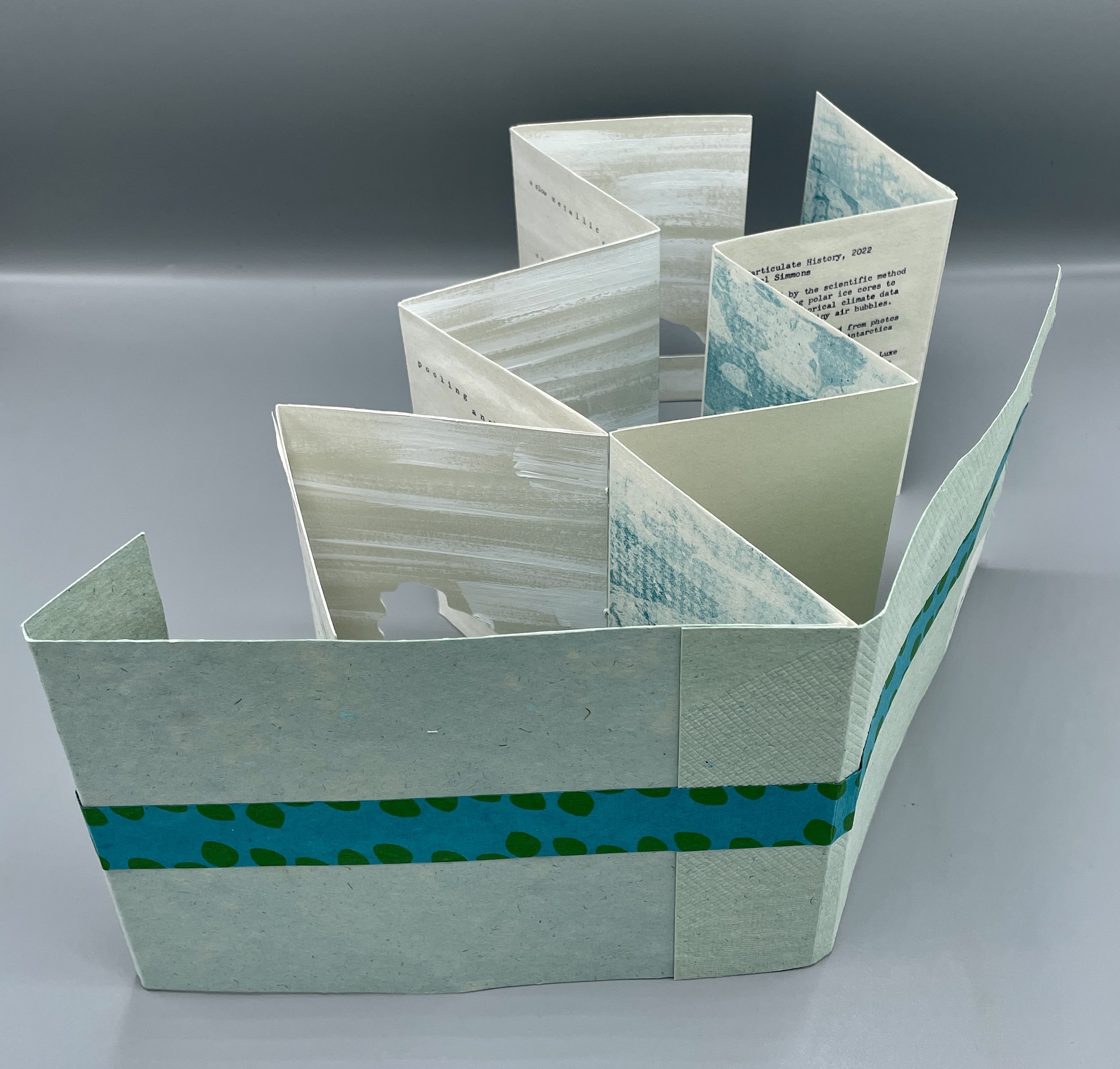 RACHEL SIMMONS particulate history,2022 Double accordion structure with handmade paper magnetic enclosure. Typewritten text, monotype and relief prints on Thai Kozo paper with gesso, thread, collage
