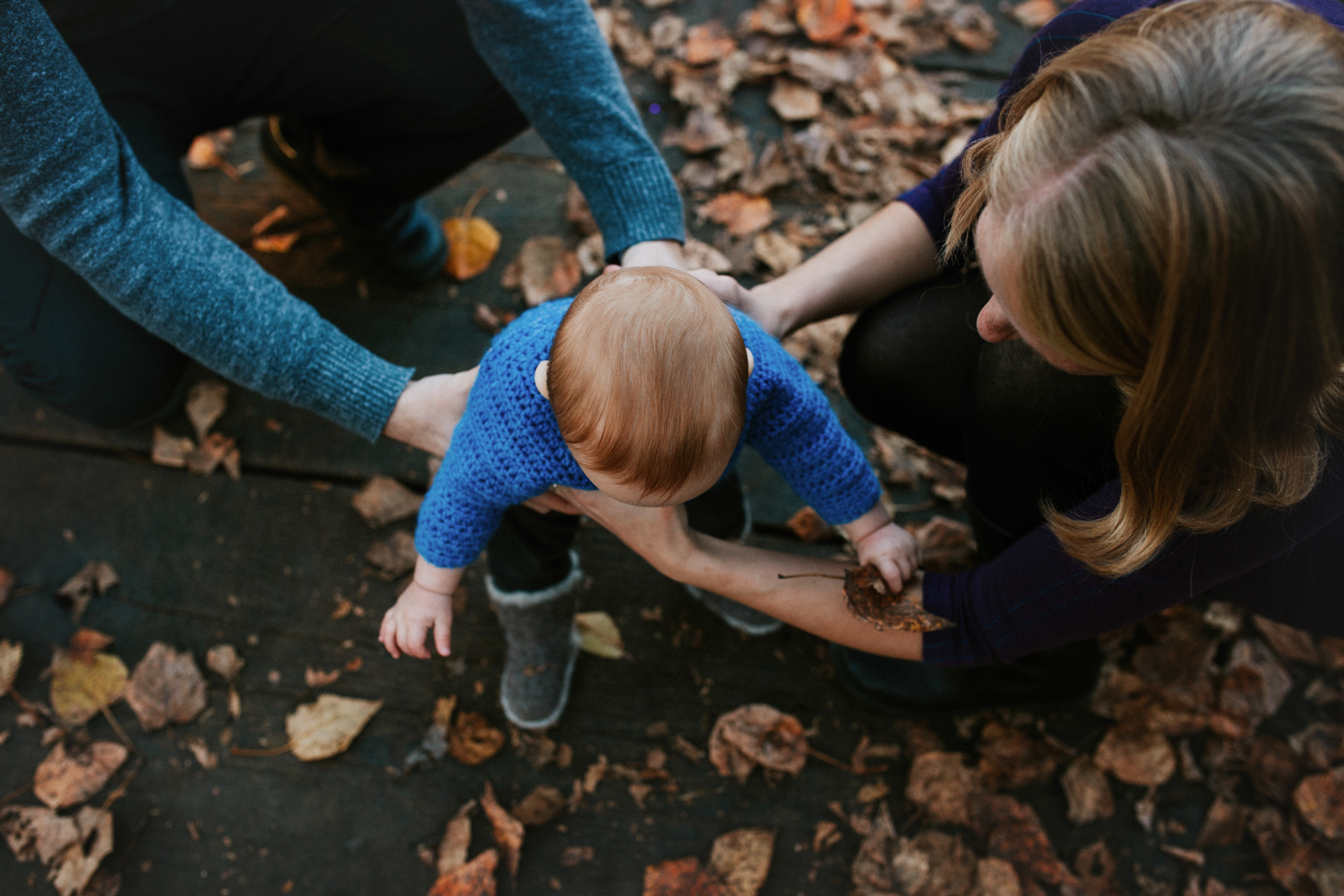 parents holding baby on bridge
