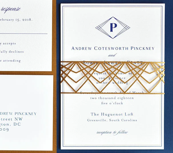 Detail of a gold geometric invitation belly band designed by Sofia Invitations . Photography is by Riverland Studios in Charleston, SC. Wedding planning is by Clink Events . The wedding took place at the Huguenot Loft in Greenville, SC.