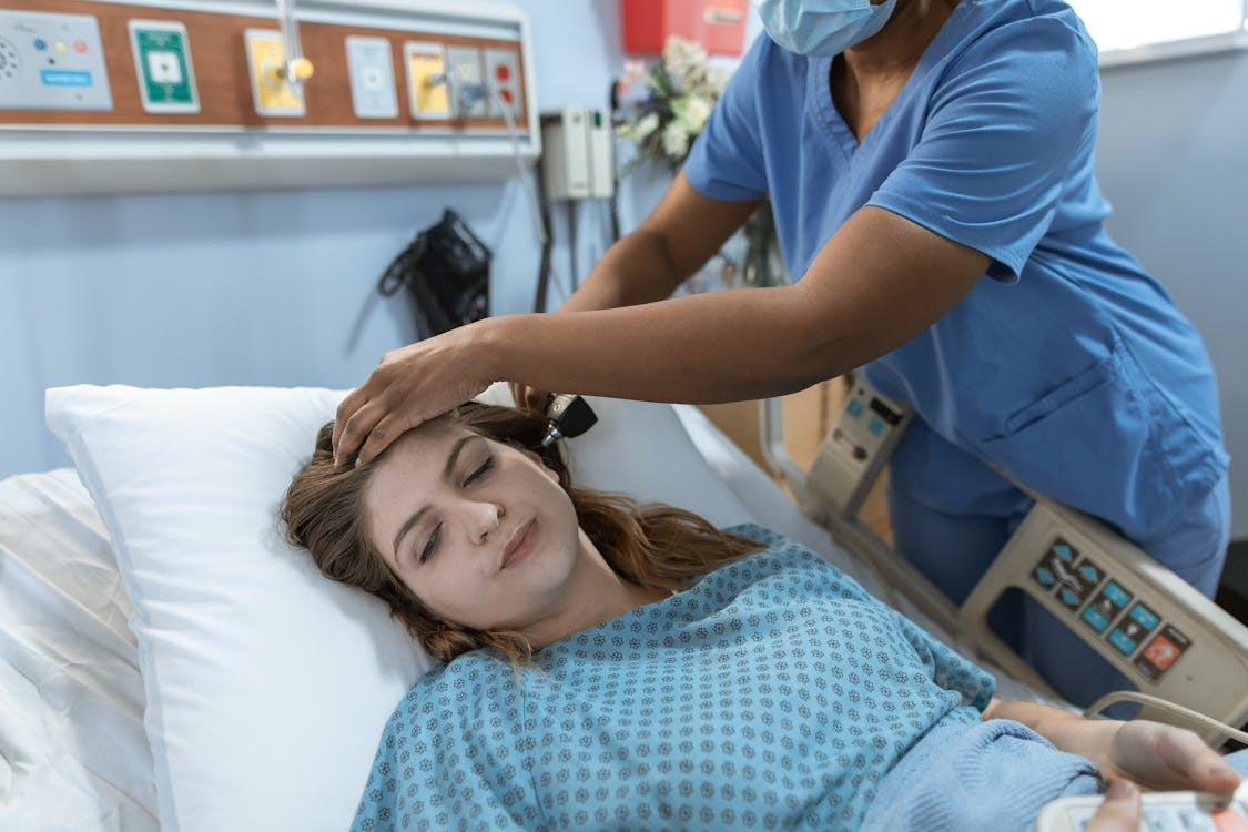 A woman recovering from labor experiences pain while a nurse checks on her.