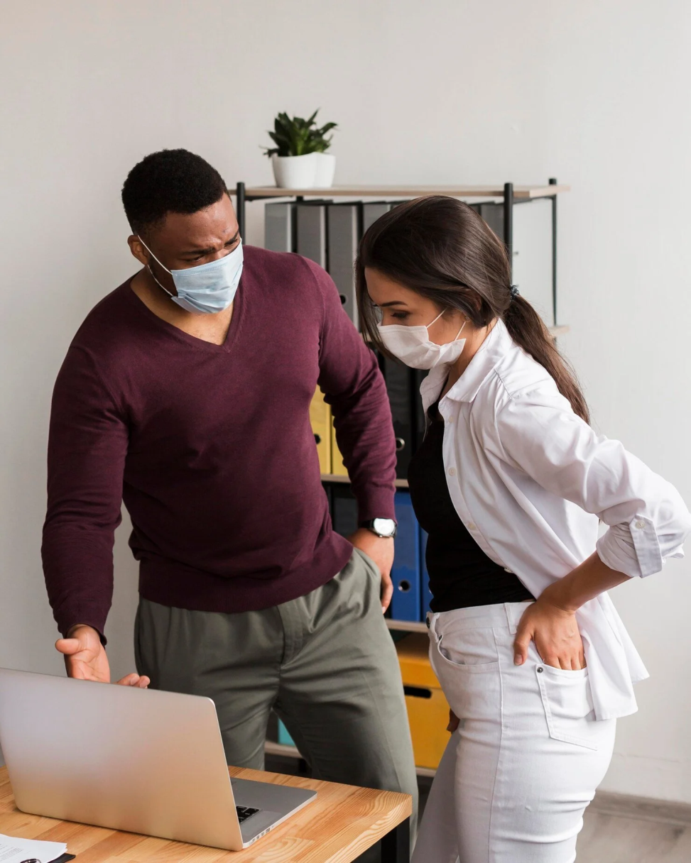 A masked professional consults with a colleague while reviewing information on a laptop, highlighting attentive care and collaboration at Stitch Texas.