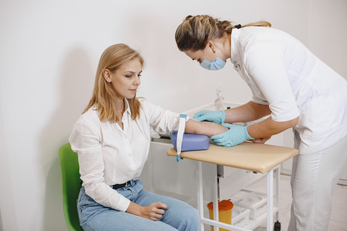 A healthcare professional takes blood from a patient’s arm.