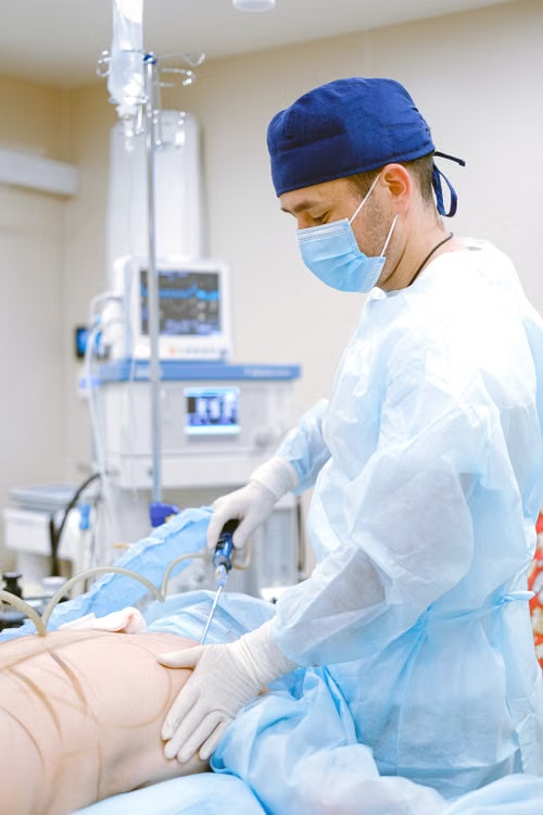 A surgeon in a scrub cap works on a patient.