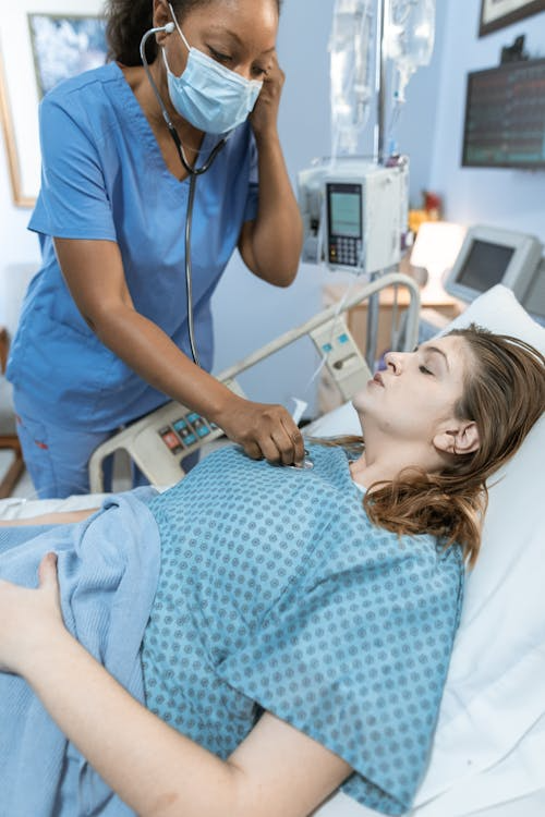 A nurse checks a patient in bed.