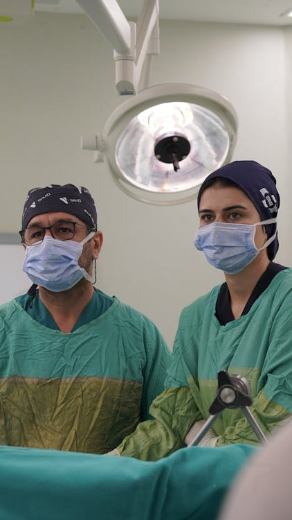 Two members of a surgical team wear the same colored cap.