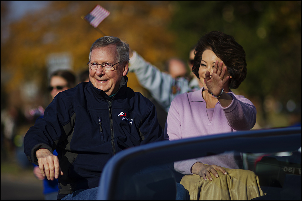  Senate minority Leader Mitch Connell, left, waves to parade watchers with his wife Elaine Chao, right, as they ride in the 50th annual Veteran's Day Parade in Madisonville, Ky. on Sunday, November 2, 2014. Brian Powers/Special to the Courier-Journal