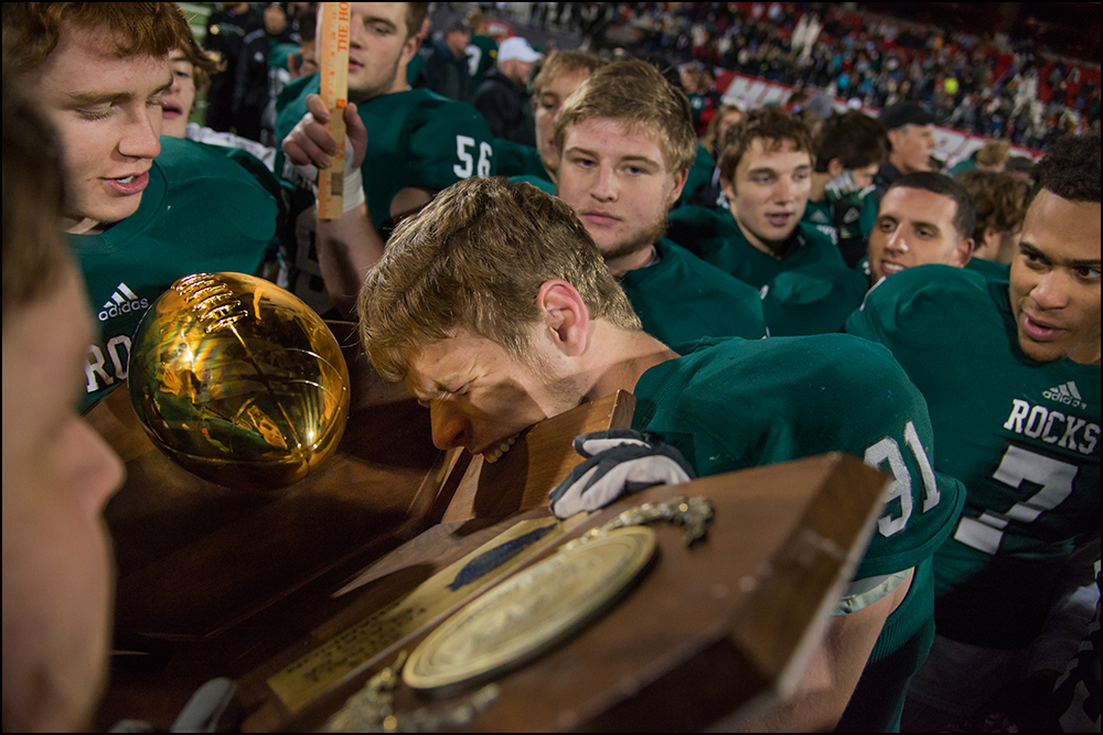 Trinity's Landon Corolla bites the championship trophy after the Shamrocks defeated Dixie Heights 47-14 during their KHSAA Commonwealth Gridiron Bowl game at Western Kentucky University in Bowling Green, KY on Saturday, December 6, 2014. Photo by Br