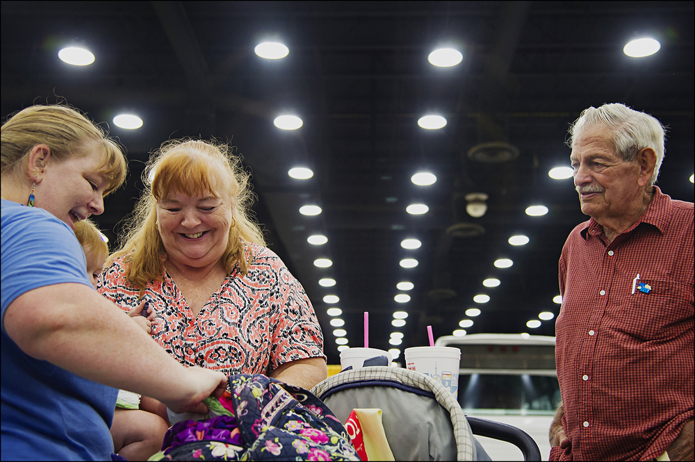  Louisville resident Amanda Mayhew, left, and her mother Teri Eisenmenger, center, finish changing Mayhew's daughter, Caramia's diaper during the Kentucky State Fair in Louisville, KY as her grandfather, Berlin Cook watches on Thursday, August 21, 20