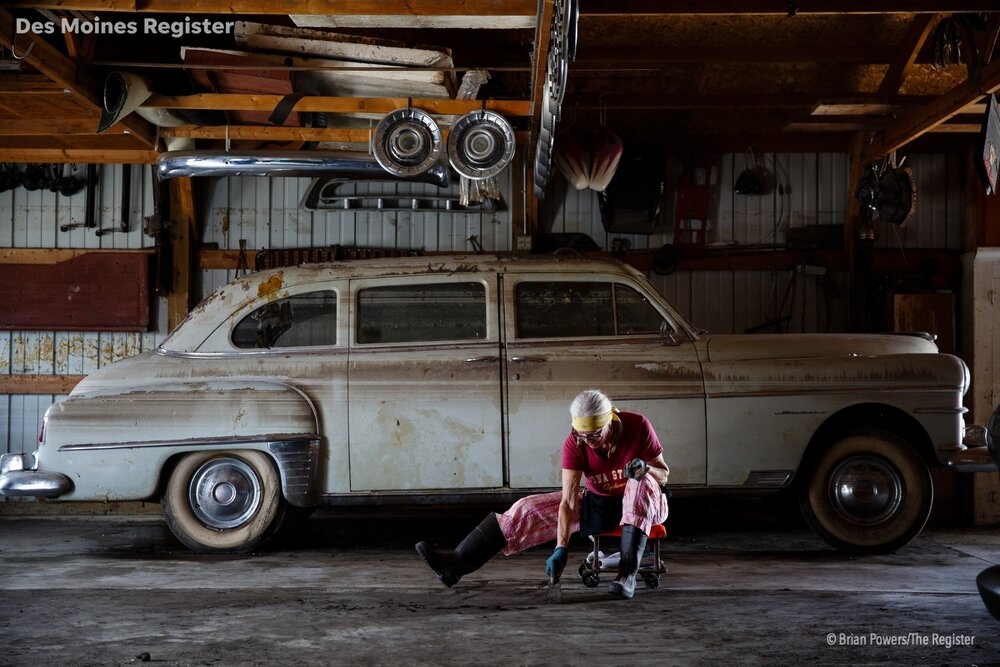  In front of a vintage car covered in water lines, Melanie Finnell scrapes the floor of one of the buildings she owns with her husband as part of their antique business on Tuesday, April 16, 2019, in Hamburg. Finnell said they plan two sell everythin