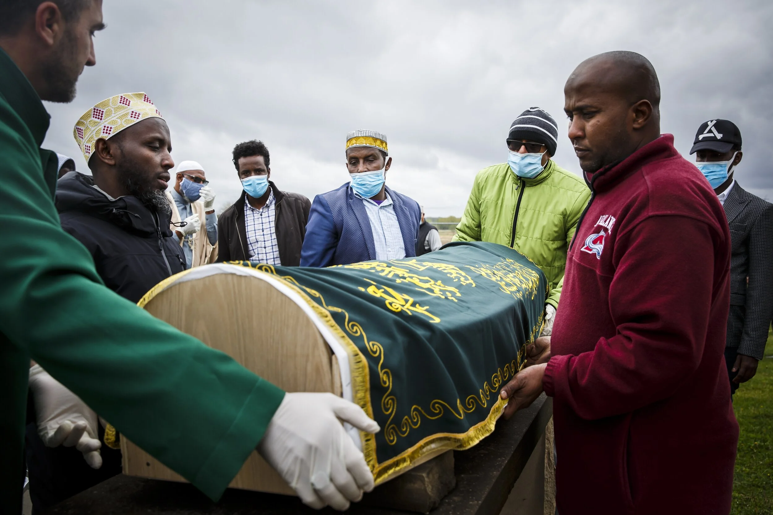  Siat Bulle, 43, stepfather of Abdullahi "Abdi" Sharif, center, helps place him on a stand for a prayer before taking him to his final resting place in the cemetery at the Islamic and Cultural Center Bosniak of Des Moines on Tuesday, May 5, 2020, in 