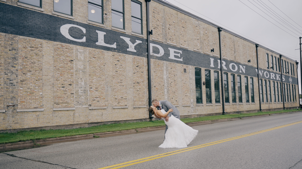 Bride and groom dip kissing outside Clyde Iron Works building.png
