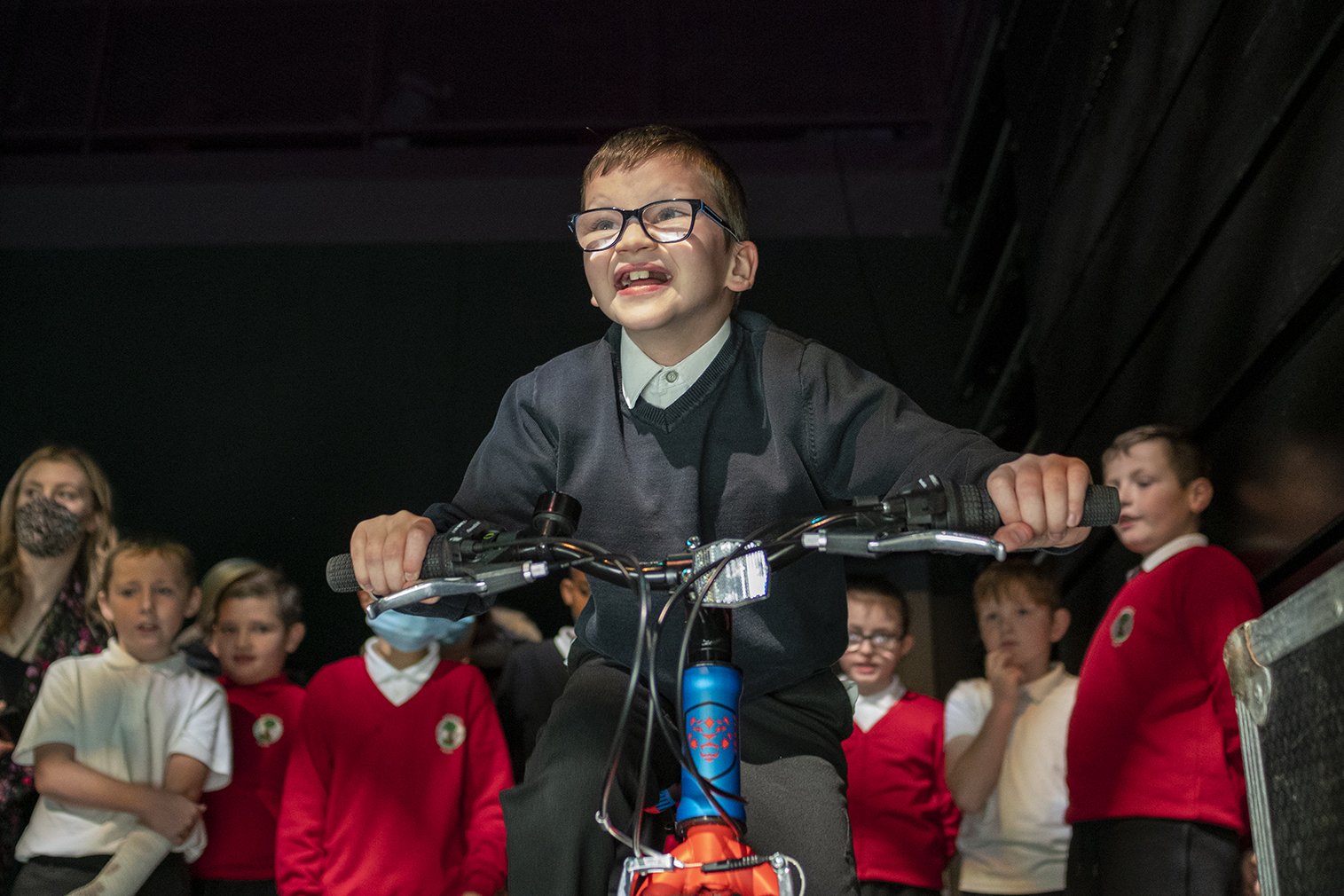  Pupil cycling a bike with his classmates behind him 