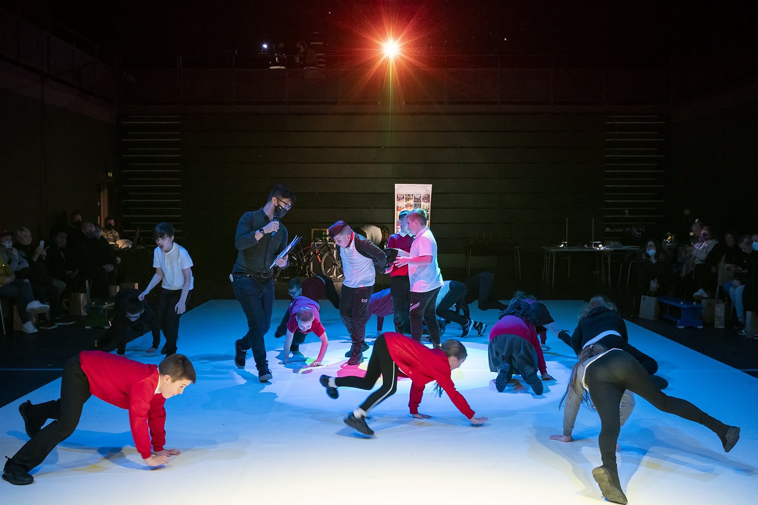  Pupils crawling across the stage with a group of pupils standing in a circle in the centre  