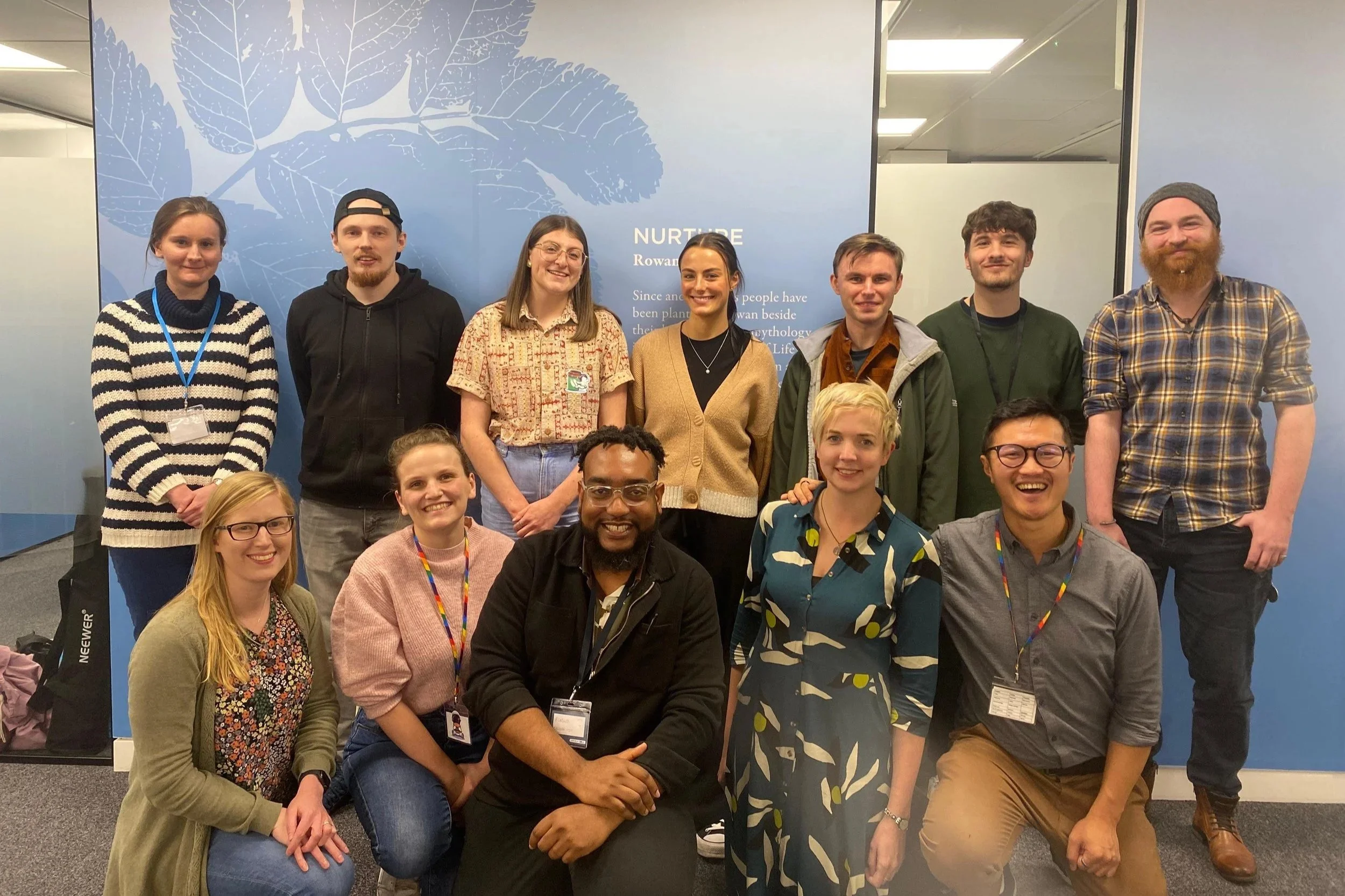 A group of action researchers from the Curiosity in Action programme, including youth workers and scientists, posing together with smiles in a team-style group photo.