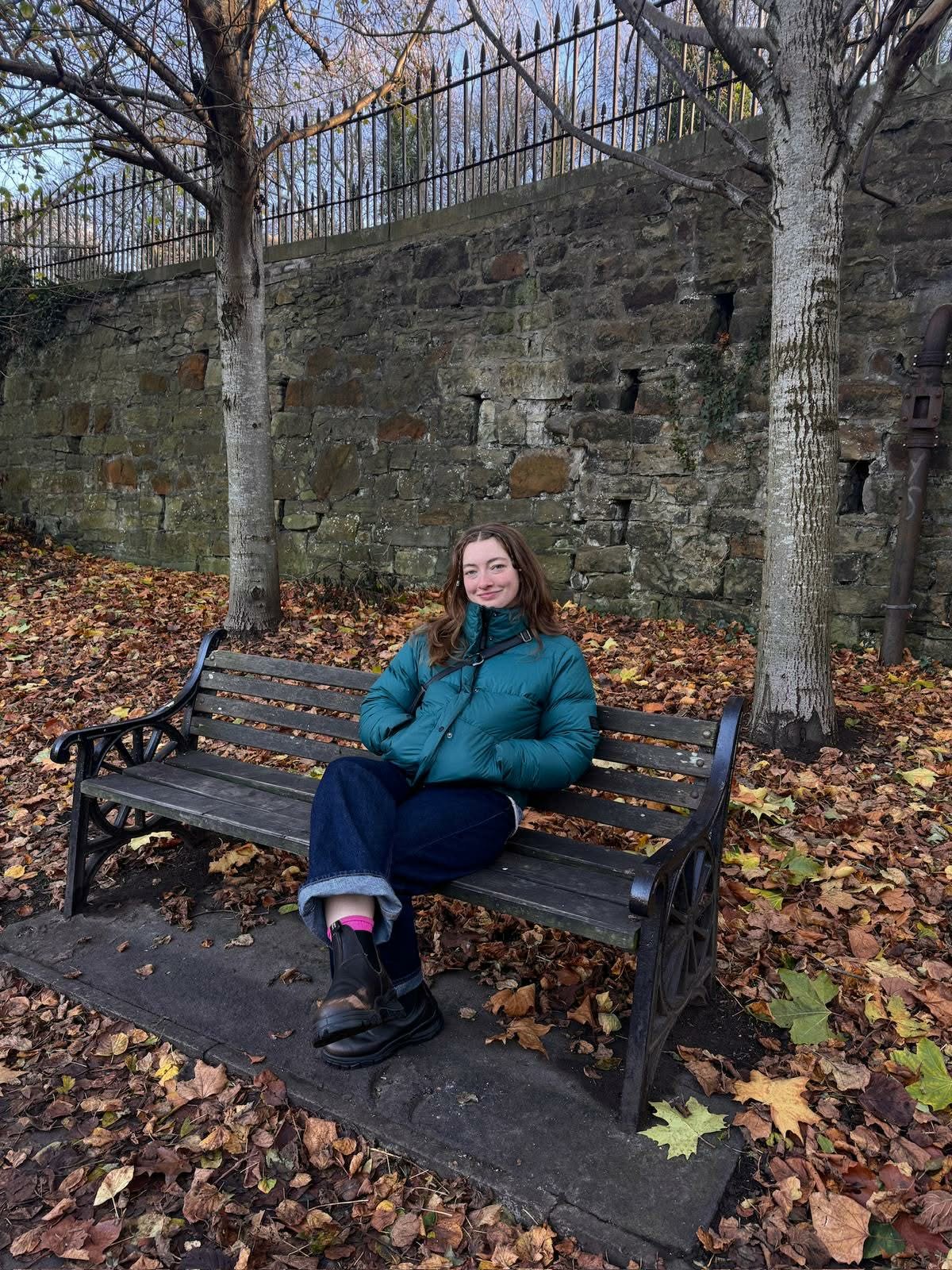 Sophie sat on a bench outdoors, on an autumn day
