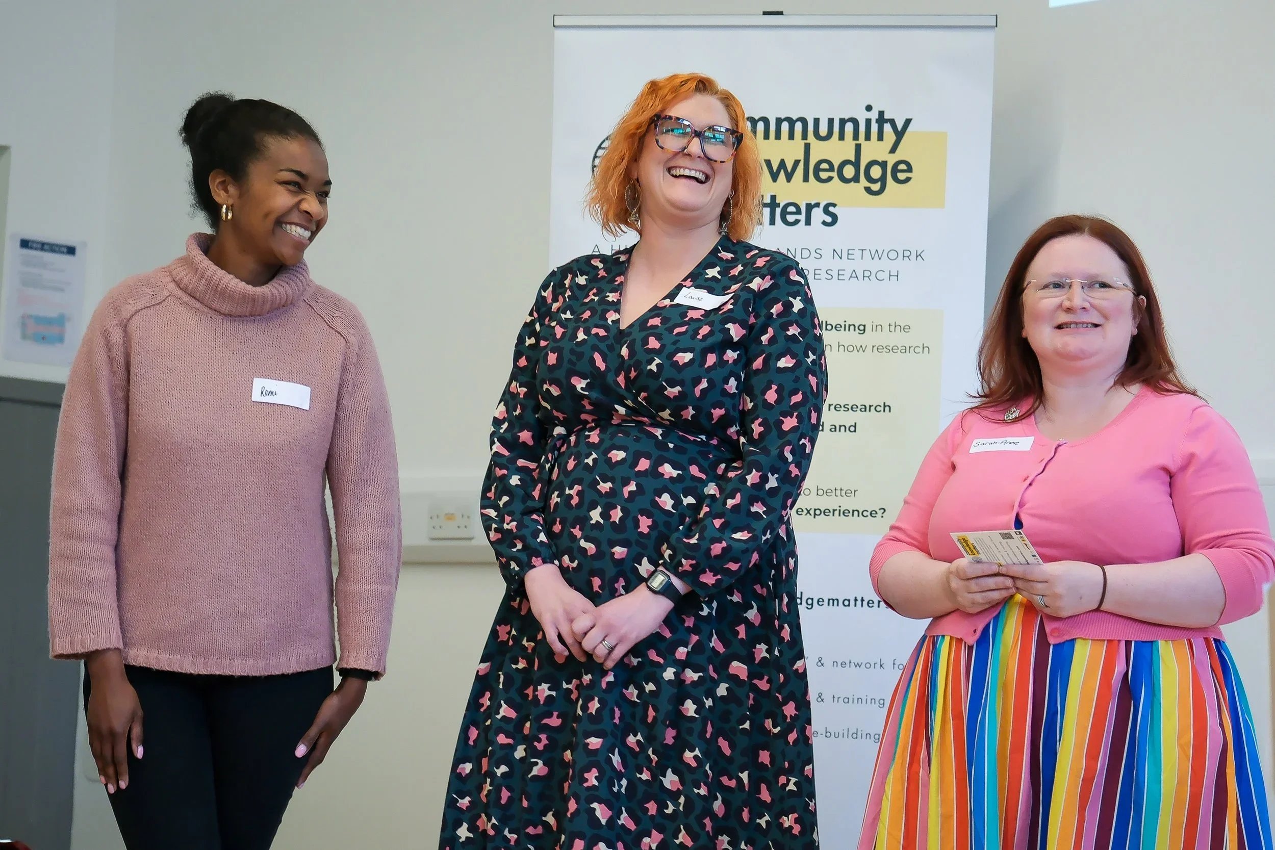 Three participants smiling and presenting at the 2024 Community Knowledge Matters Gathering, capturing the spirit of shared learning.