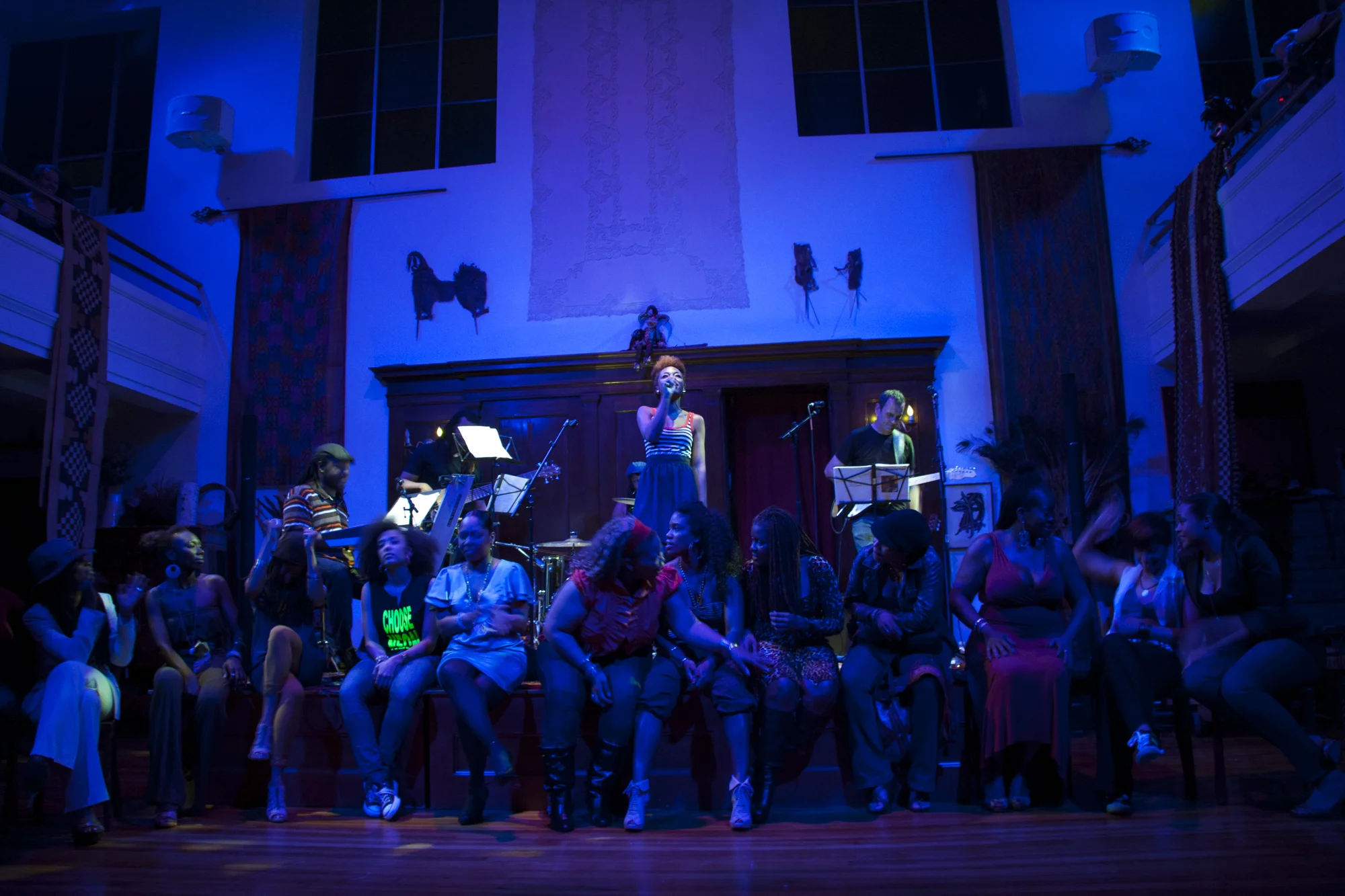 Kim on stage, about to close the show. Sitting on stage are all other performers that night, (Left to Right) Ki Ki Hawkins, Mahasin, Sun Singleton, Amanda Seales, Abby Dobson, Mika Deharlem, Farrah Burns, LaSonya Gunter, Asa Lovechild, Lorenda Robinson, Semaj Douglas, Maiysha