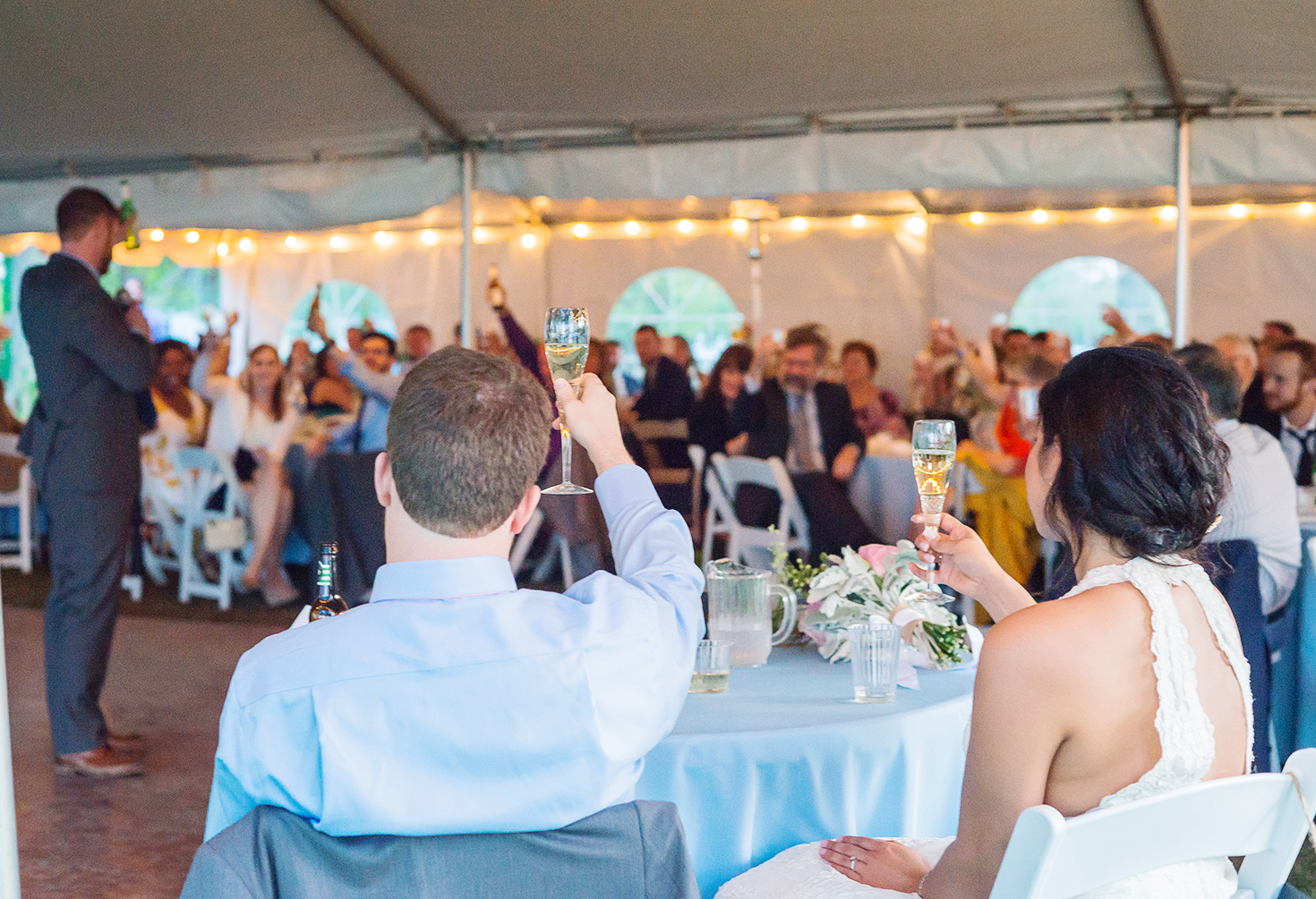 Best man gives wedding toast as bride and groom look on during sunset 