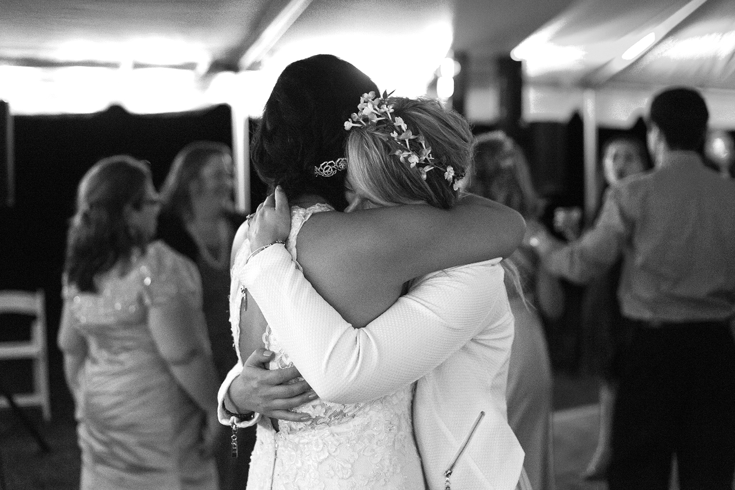 Bride and maid of honor hugging on the dance floor at Rosedale Manor in Greenwell State Park 