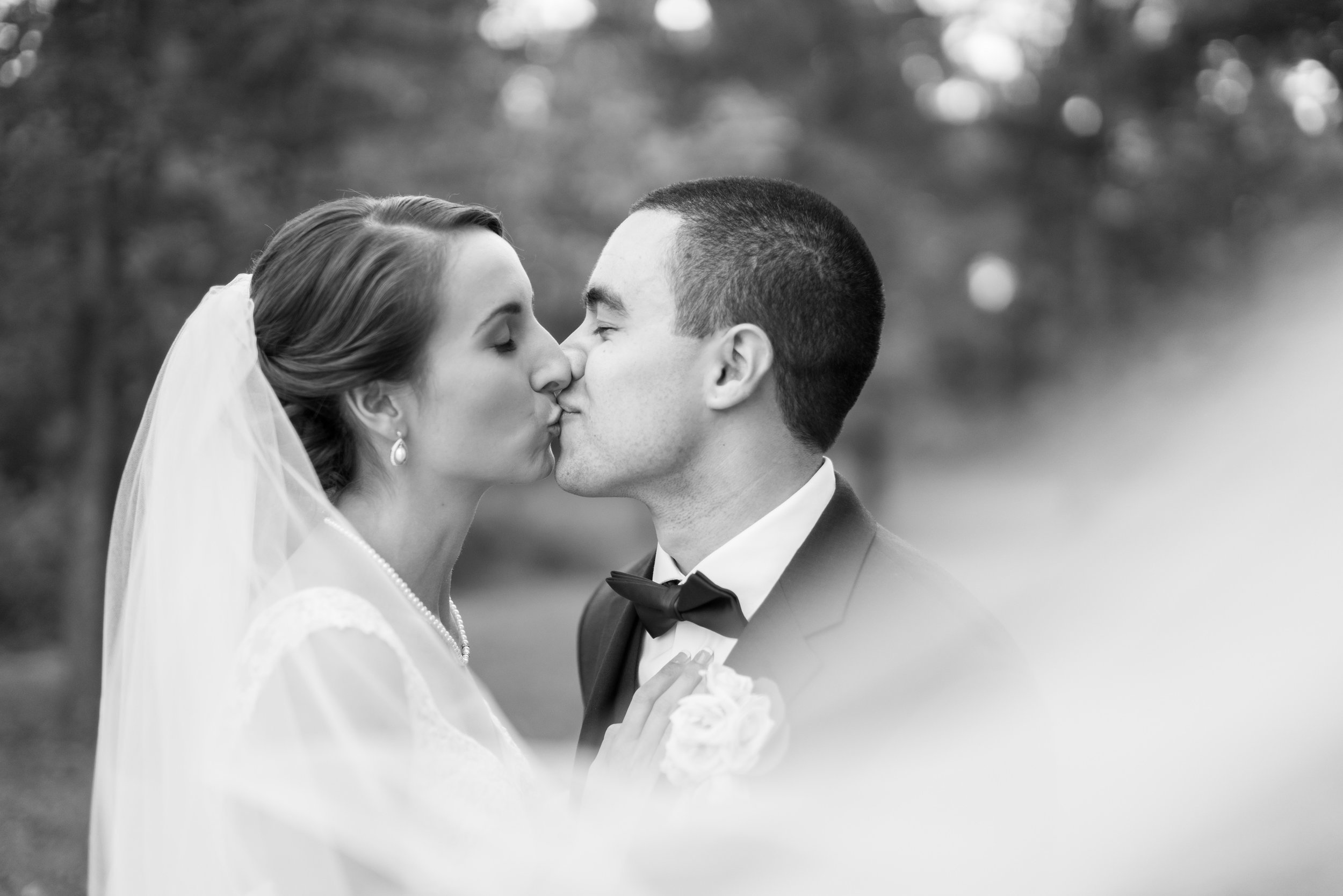 Black and white portrait of bride and groom kissing