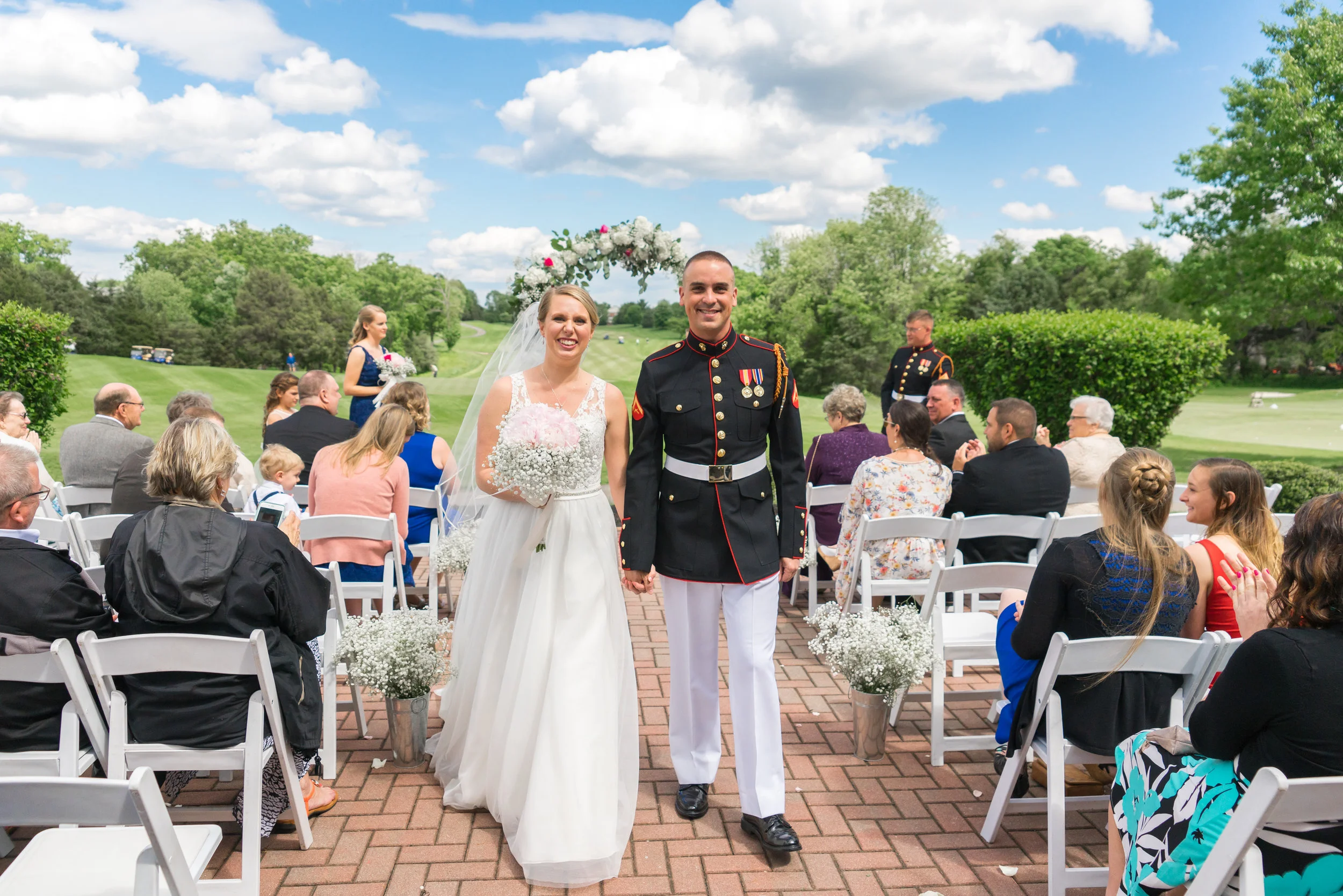 Bride and groom walking down the aisle at their summer golf course wedding