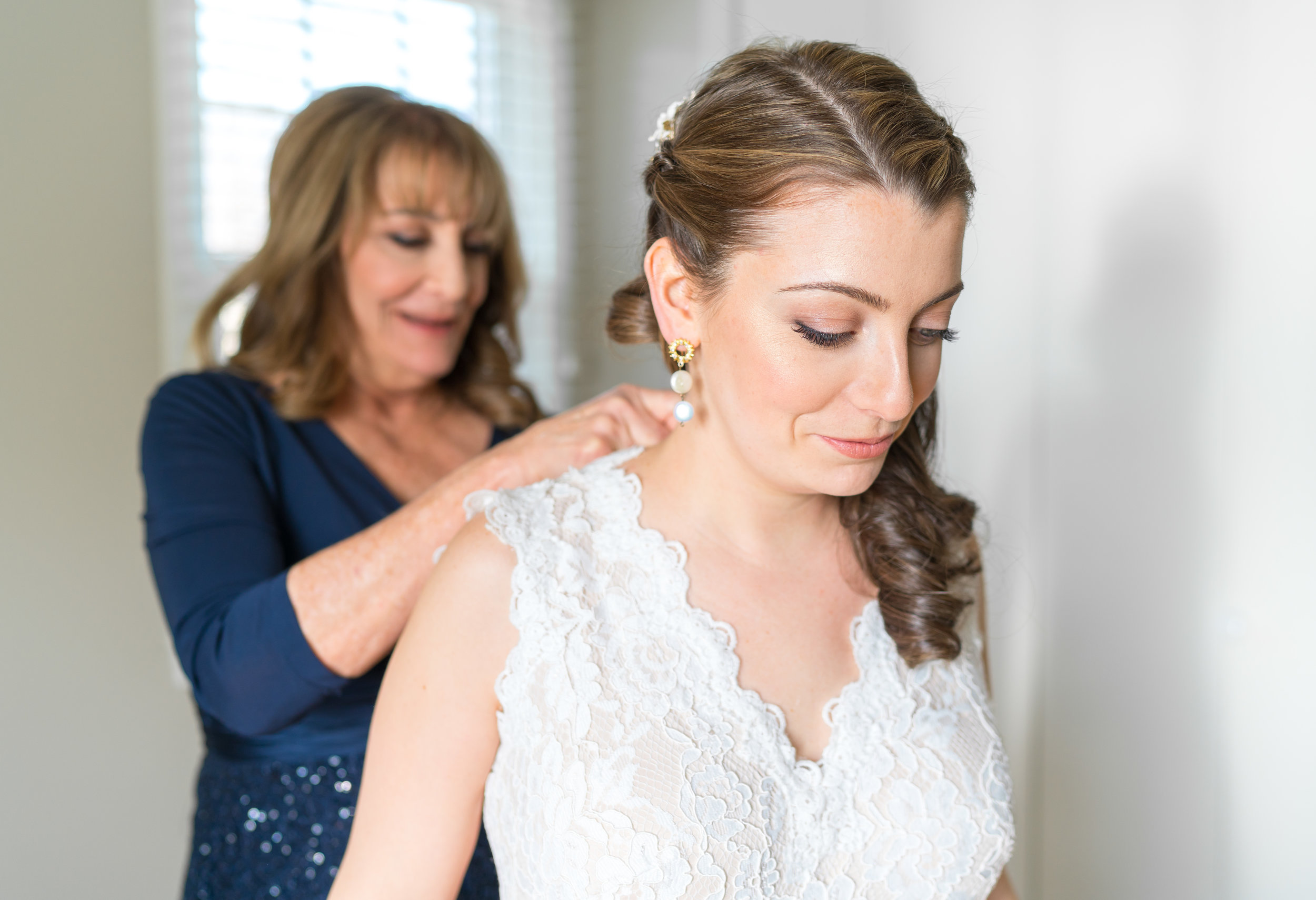 Mom buttoning bride's dress in Chevy Chase home