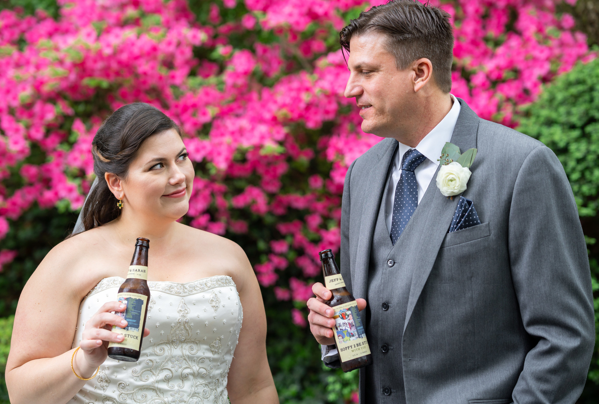 Bride and groom toasting with beer bottles with custom wedding day labels 