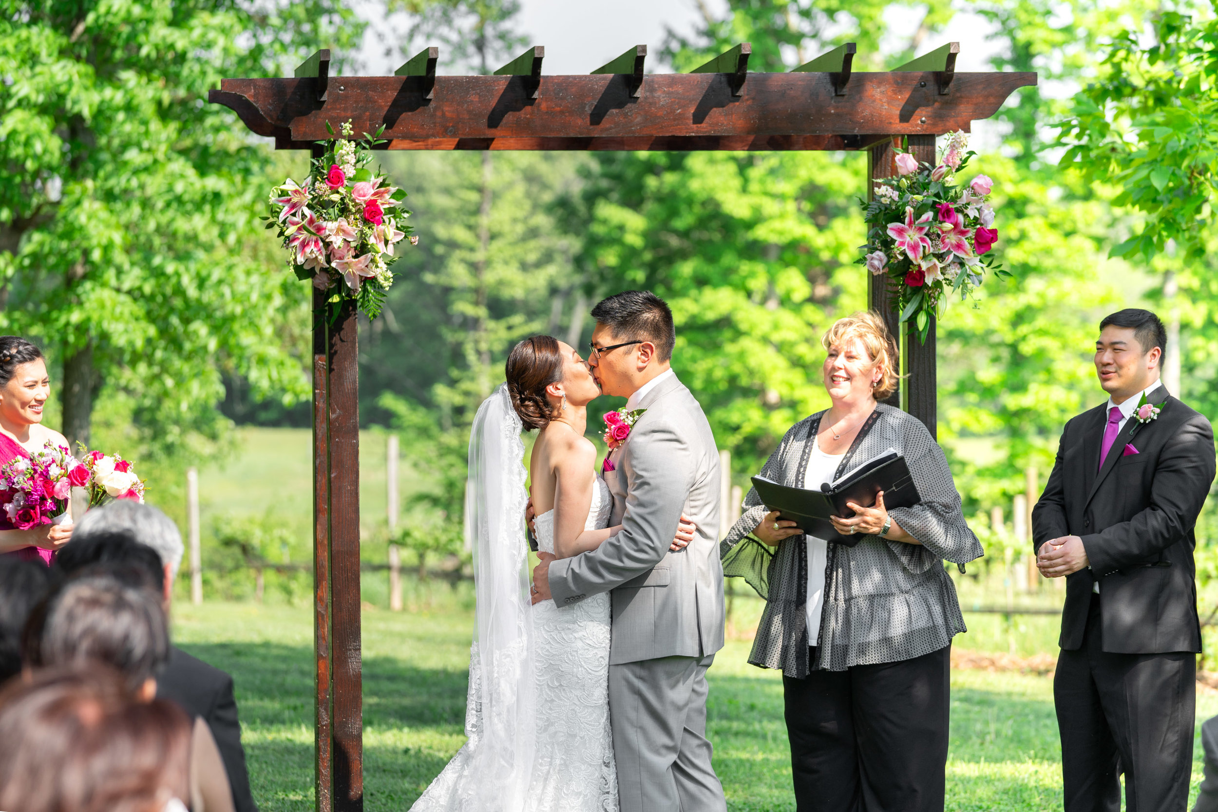 Bride and groom kiss under arch at Harvest House Lost Creek Winery