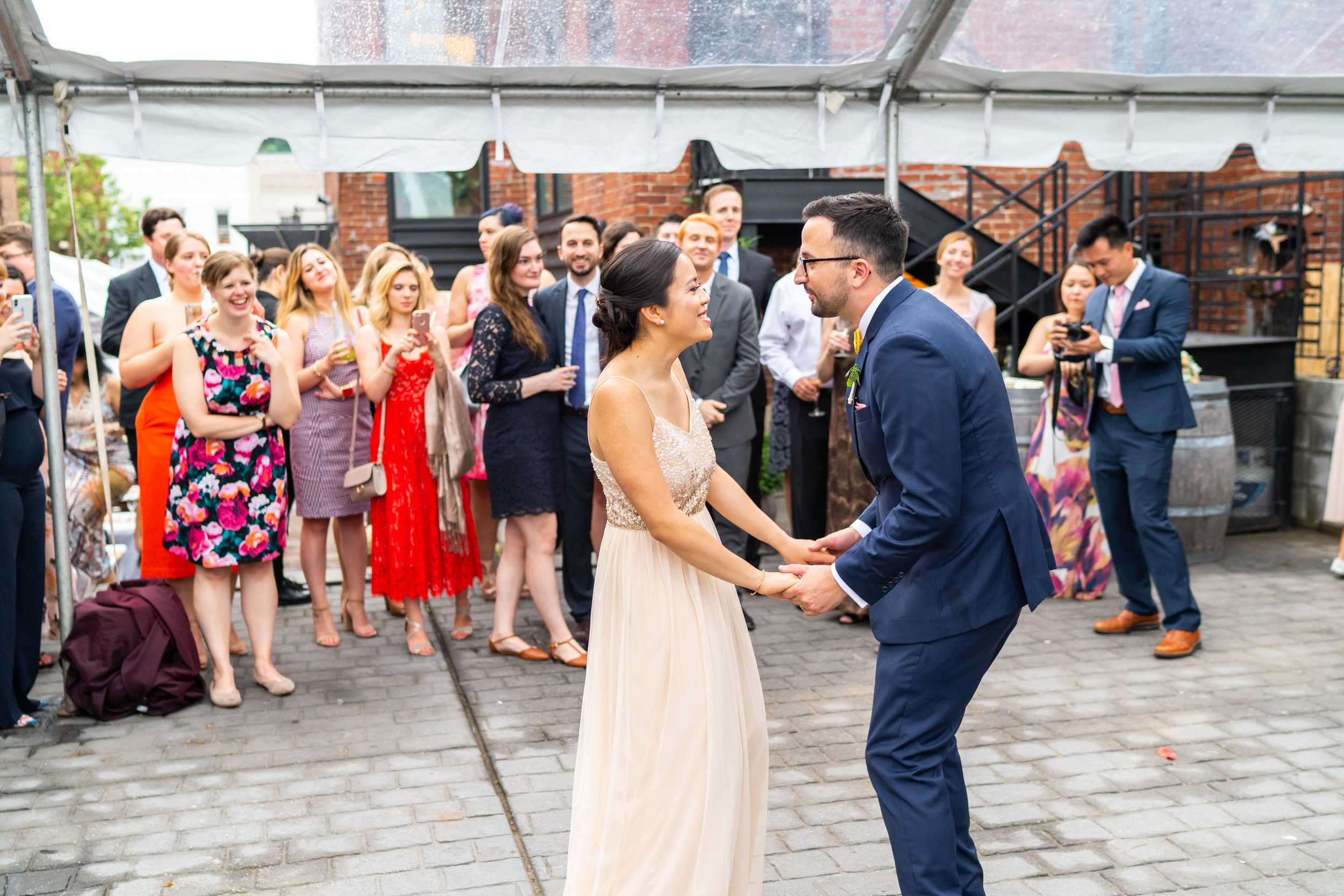 Bride and groom laugh while sharing first dance under clear tent reception at DC venue Gallery O on H