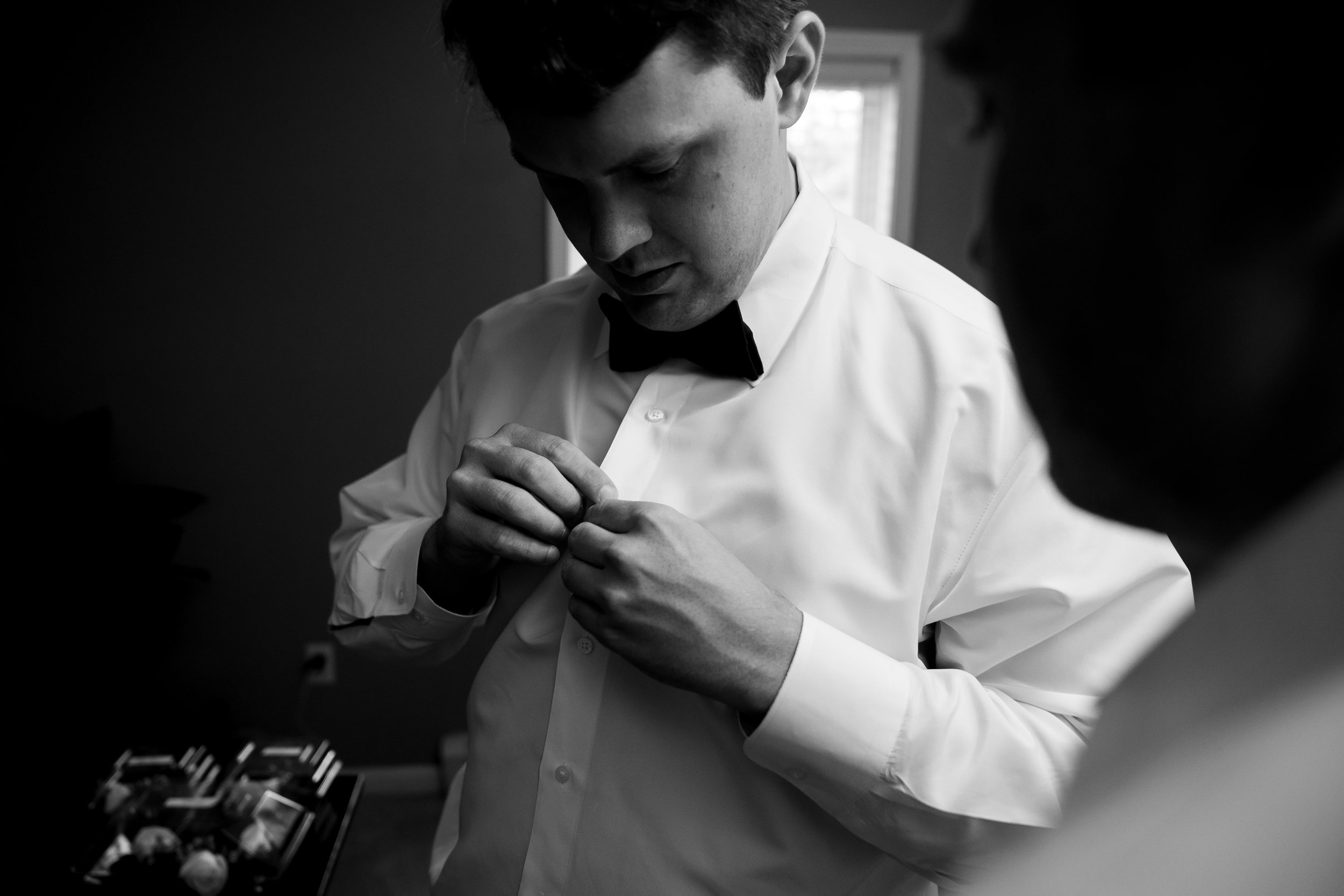 Black and white image of groom getting ready at Harvest House Lost Creek Winery
