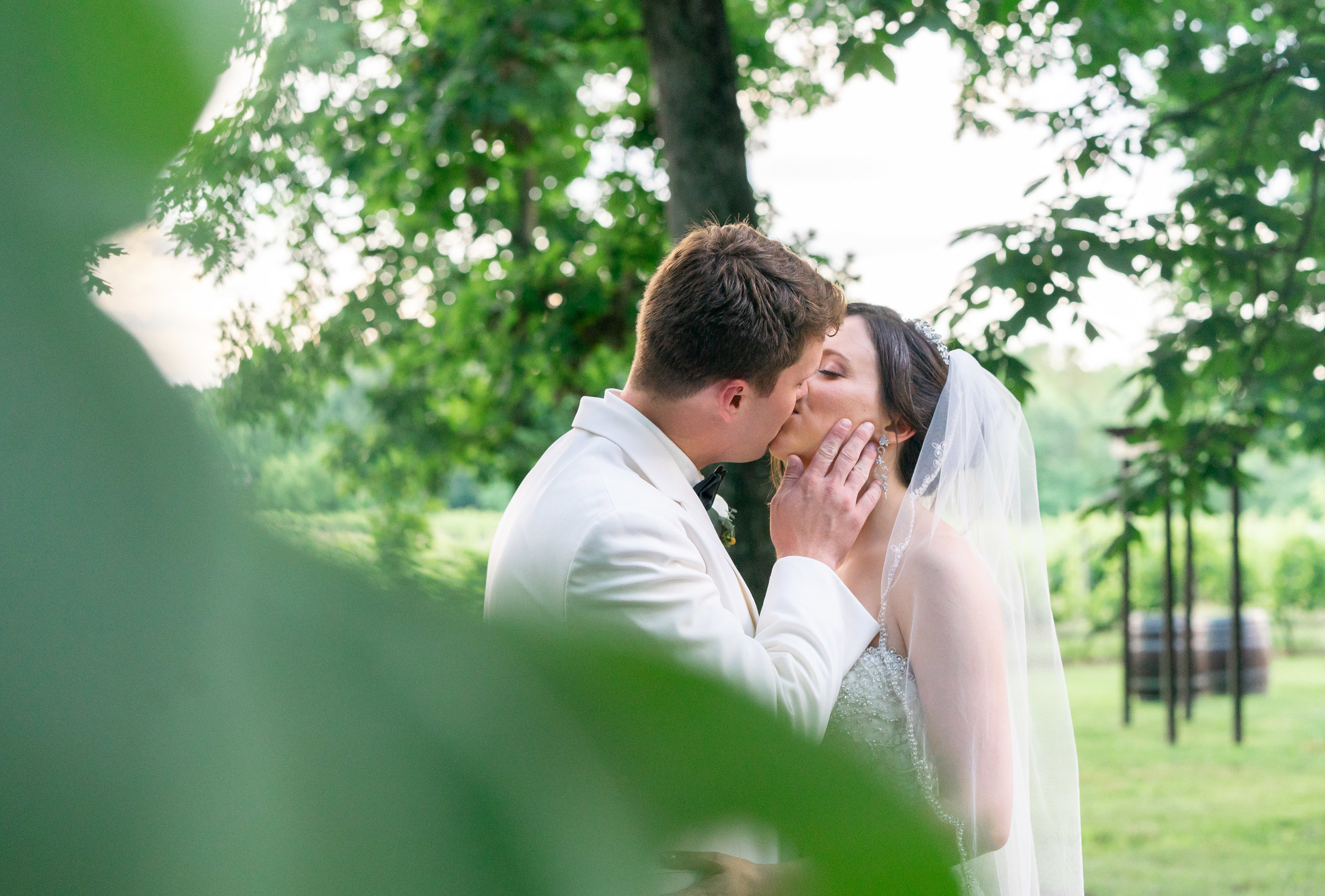 Bride and groom kissing behind the trees