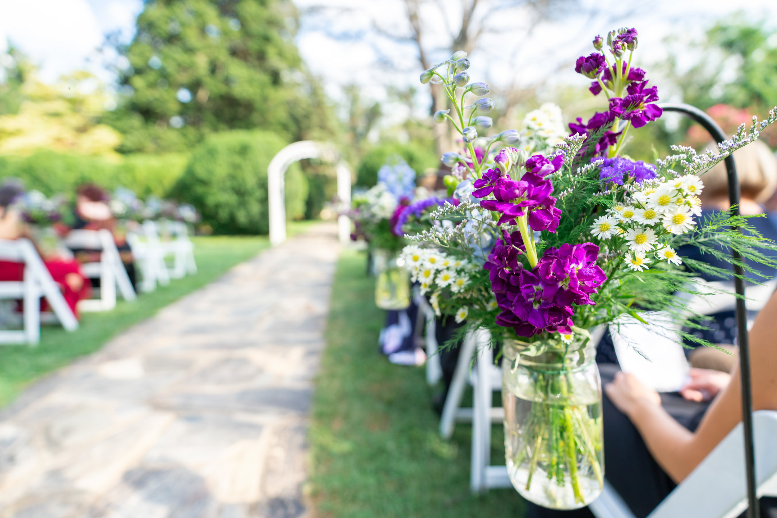 Shepherds hook with purple flowers leading down wedding aisle