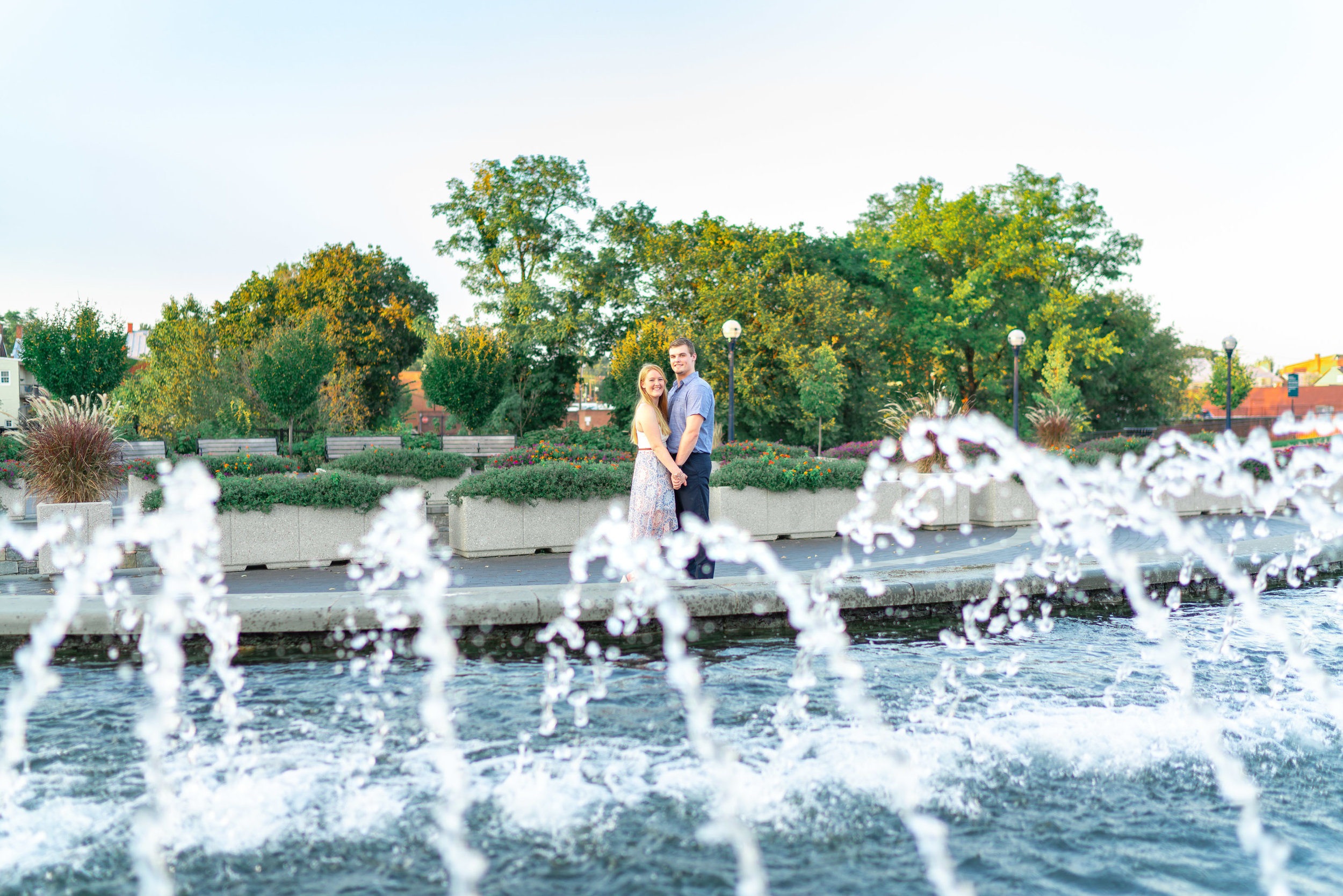 Bride and groom engaged couple standing at the fountains along downtown riverwalk in Frederick Maryland
