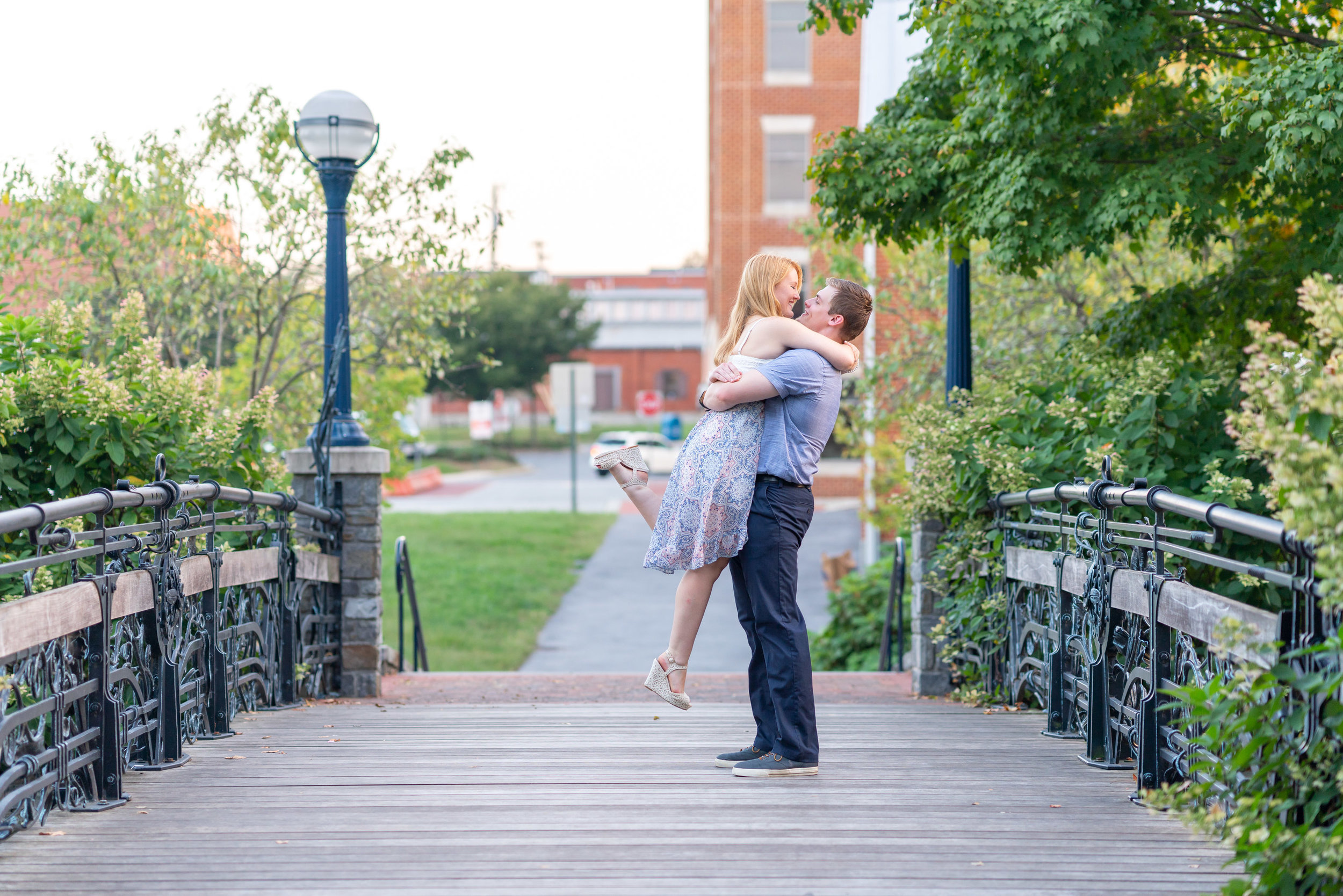 Groom lifting and kissing his bride on a bridge in Frederick Maryland downtown riverwalk