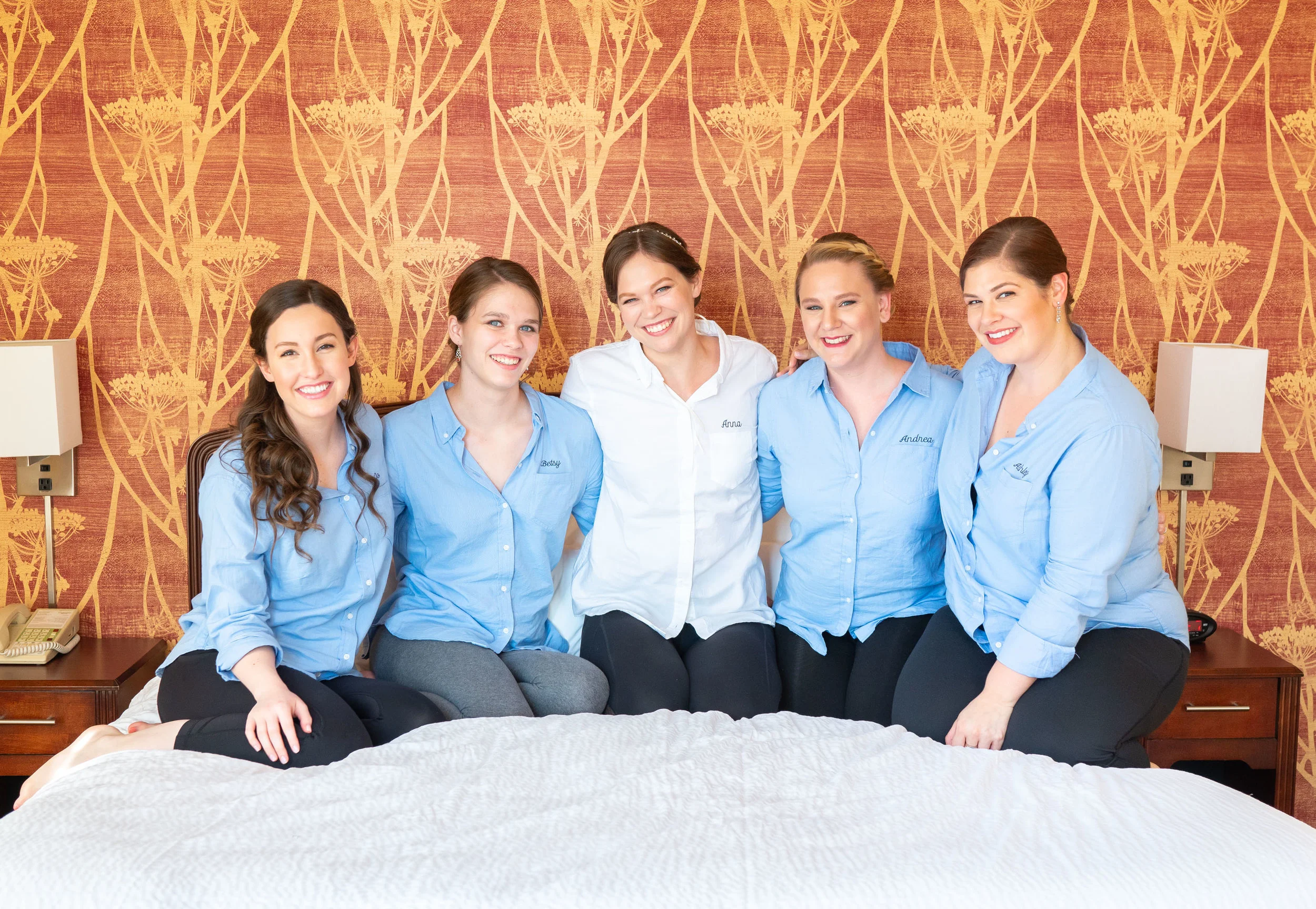 Bride and bridesmaids on bed getting ready photos in Baltimore hotel