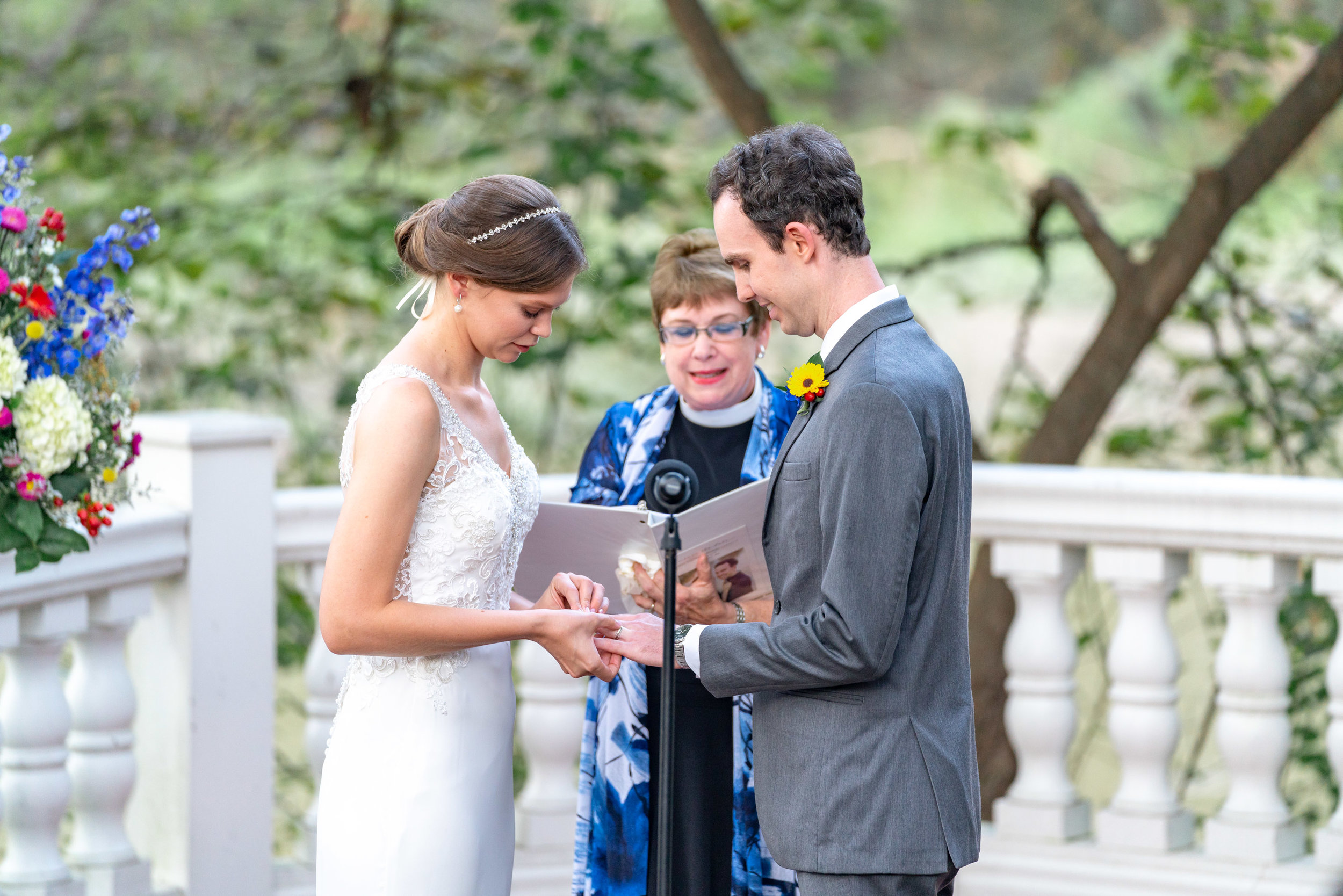 Bride is putting the ring on the groom at Elkridge Furnace Inn ceremony by the water