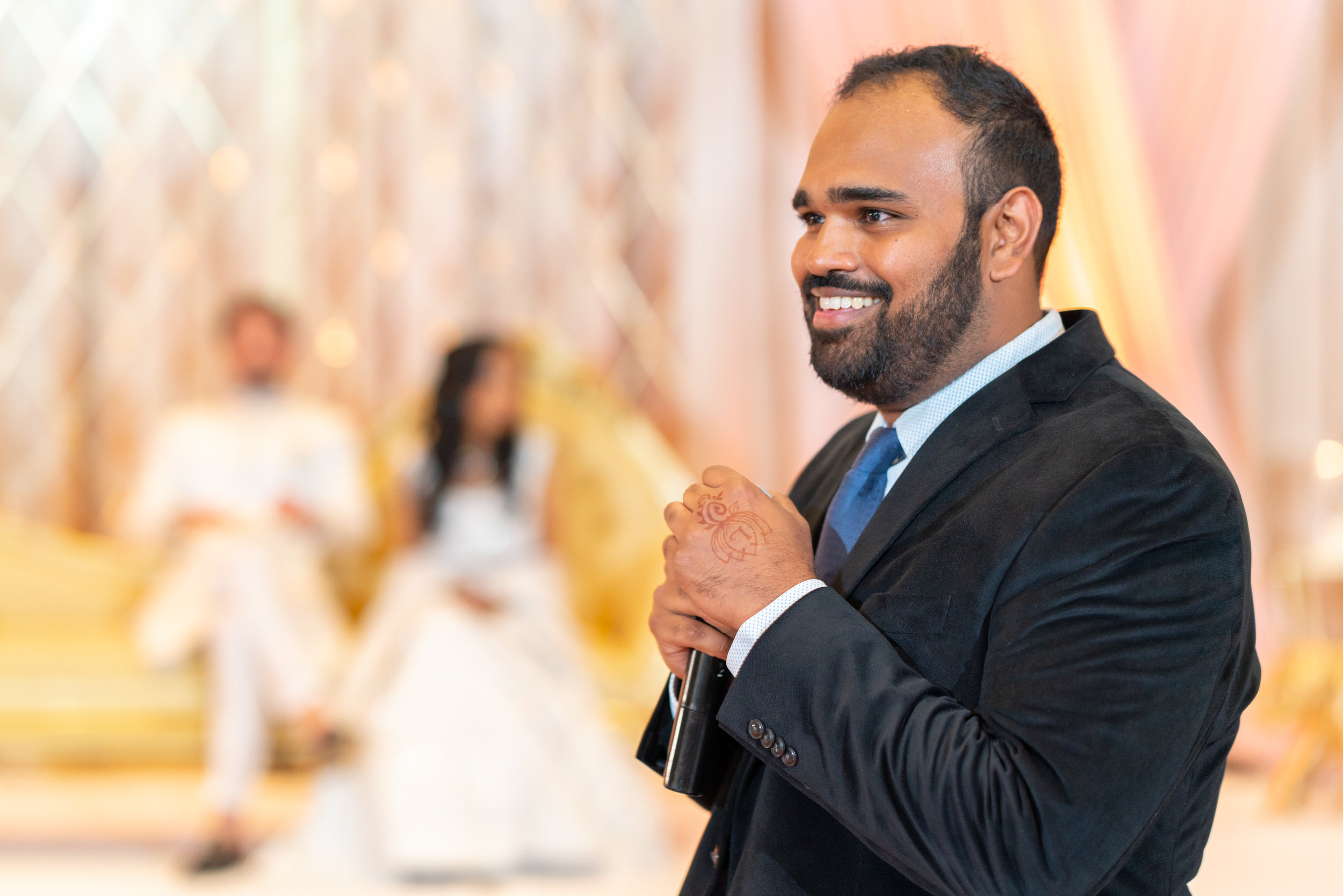 Bride's brother smiling and reading funny toast during indian wedding reception
