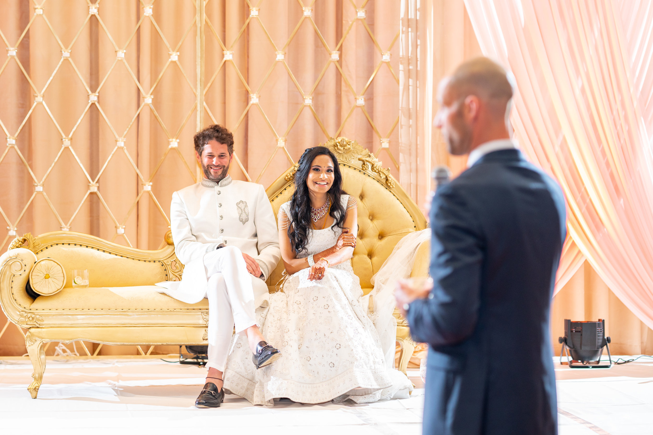 Bride and groom laughing at groom's brother's speech