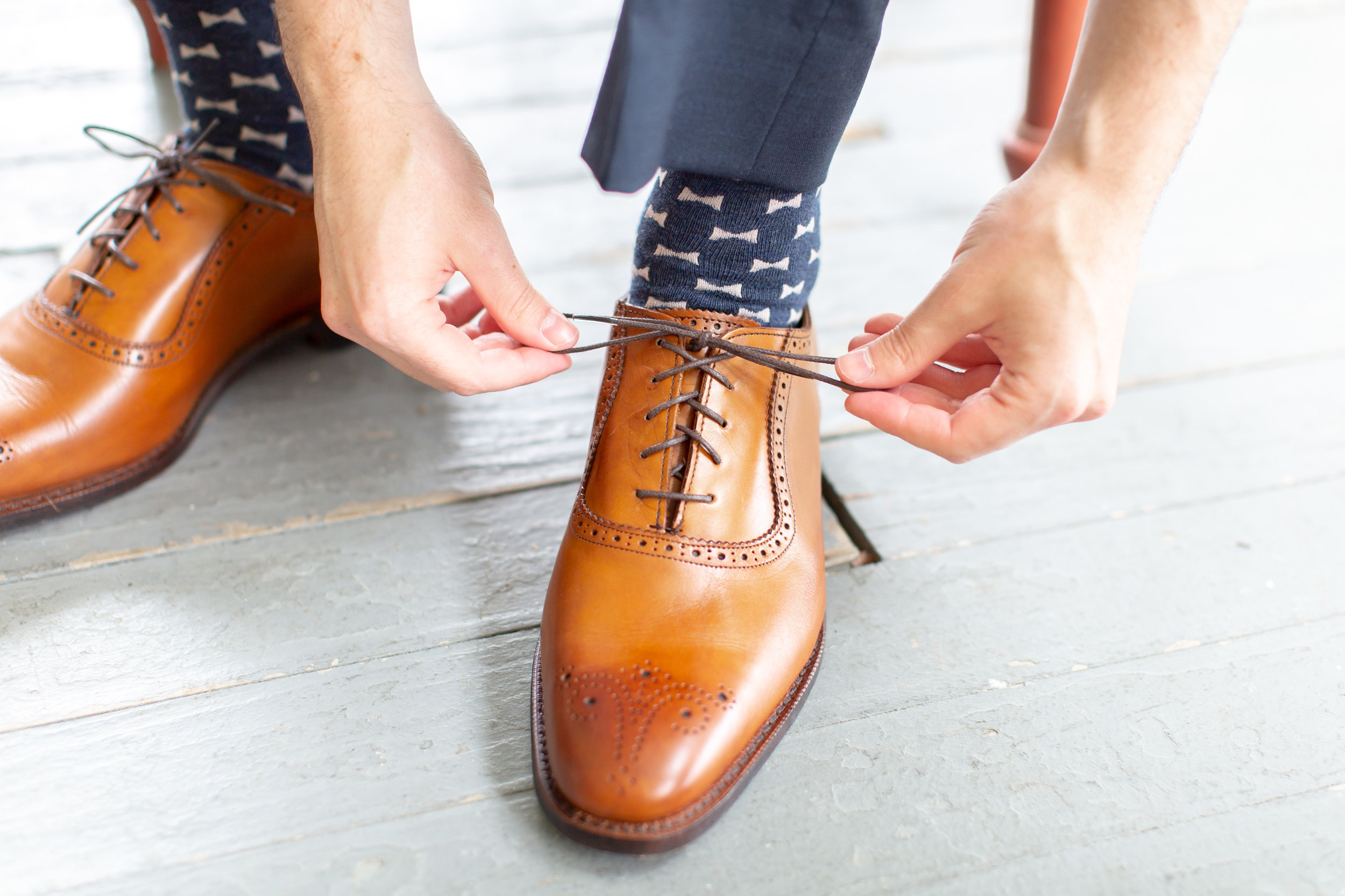 Groom tying his shoes at groom's lounge at Springfield Manor Winery and Distillery