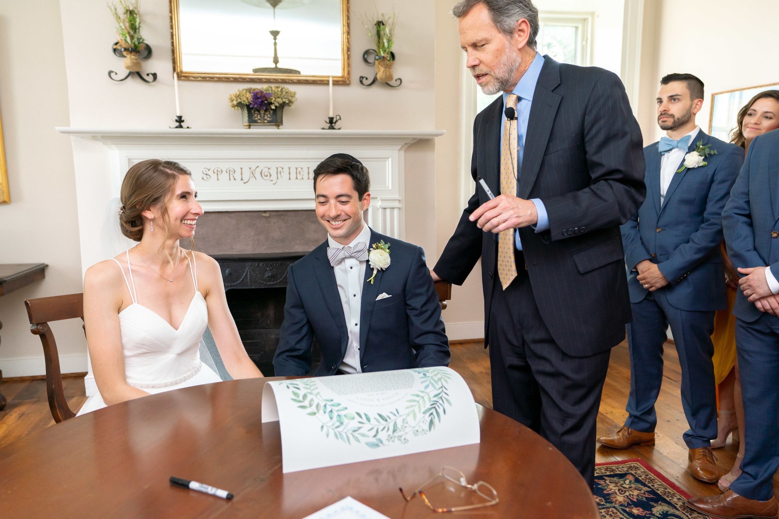 Bride and groom signing the ketubah in a side room at Springfield Manor