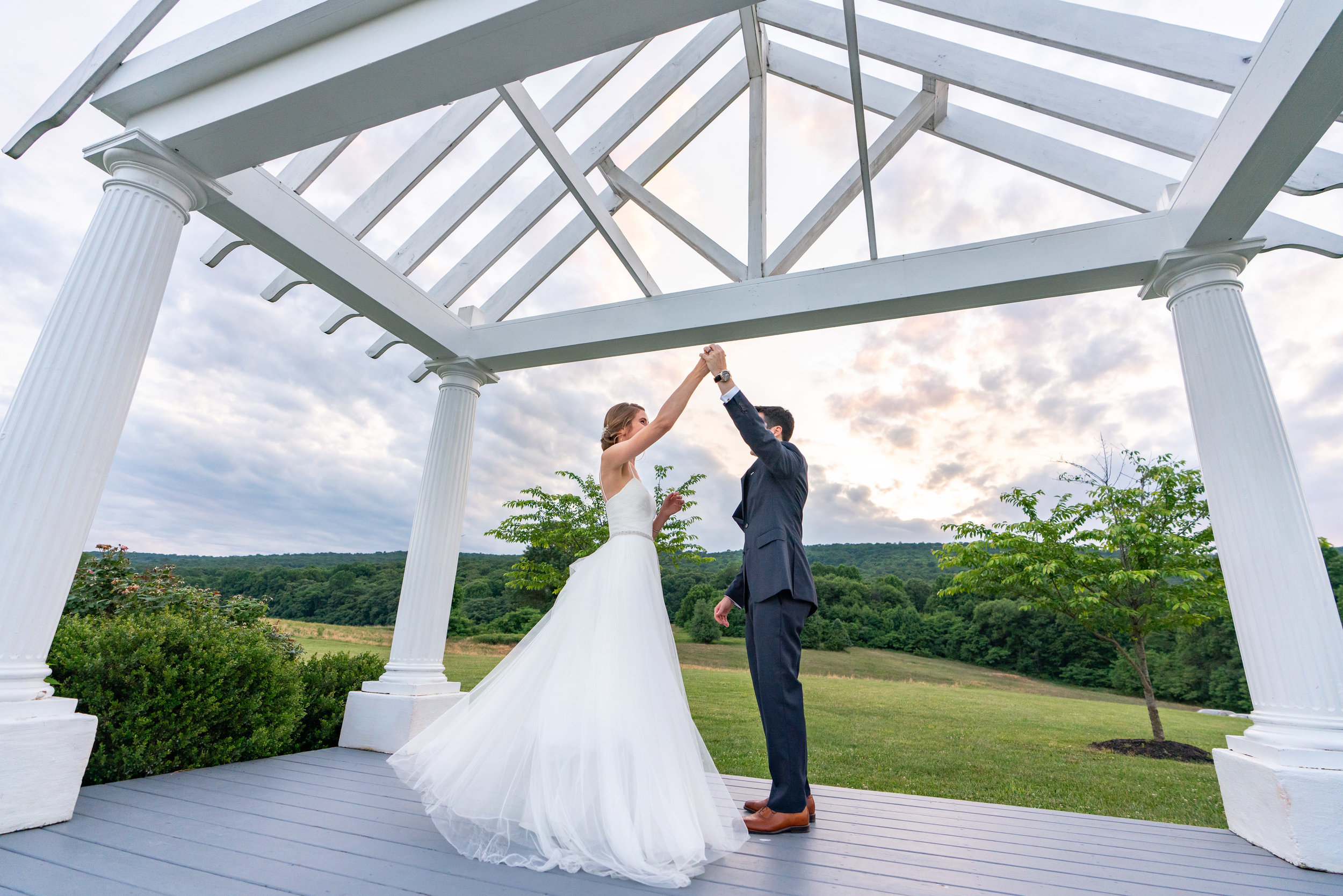 Groom twirling bride under incredible awning and sunset over sugarloaf mountain wedding venue