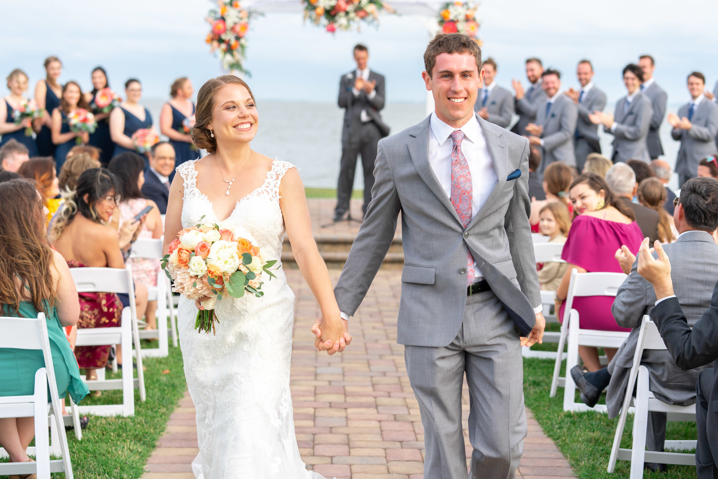 Bride and groom smiling holding hands walking down the aisle at Rehoboth Beach Country Club