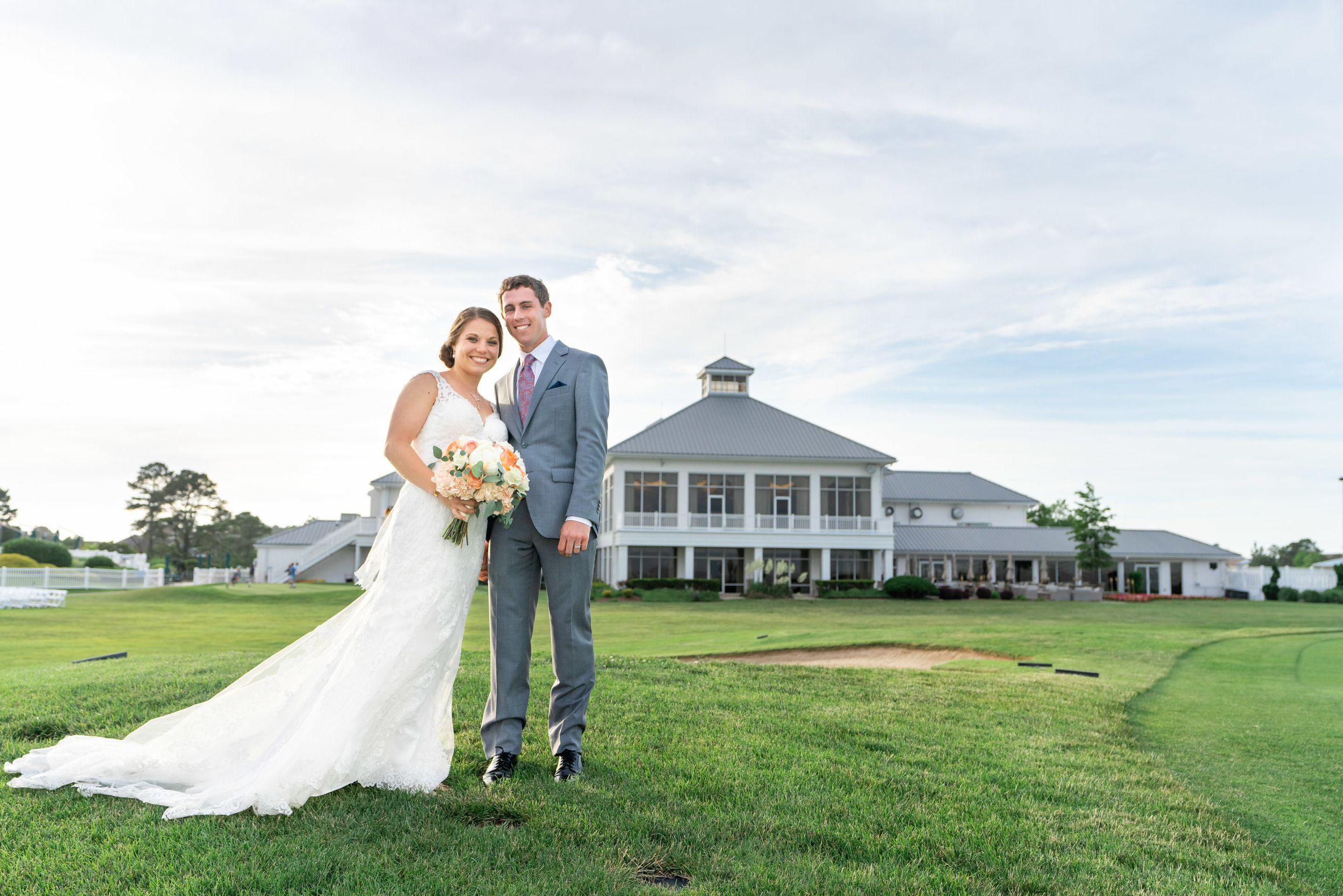 Bride and groom standing in front of Rehoboth Beach Country Club during sunset