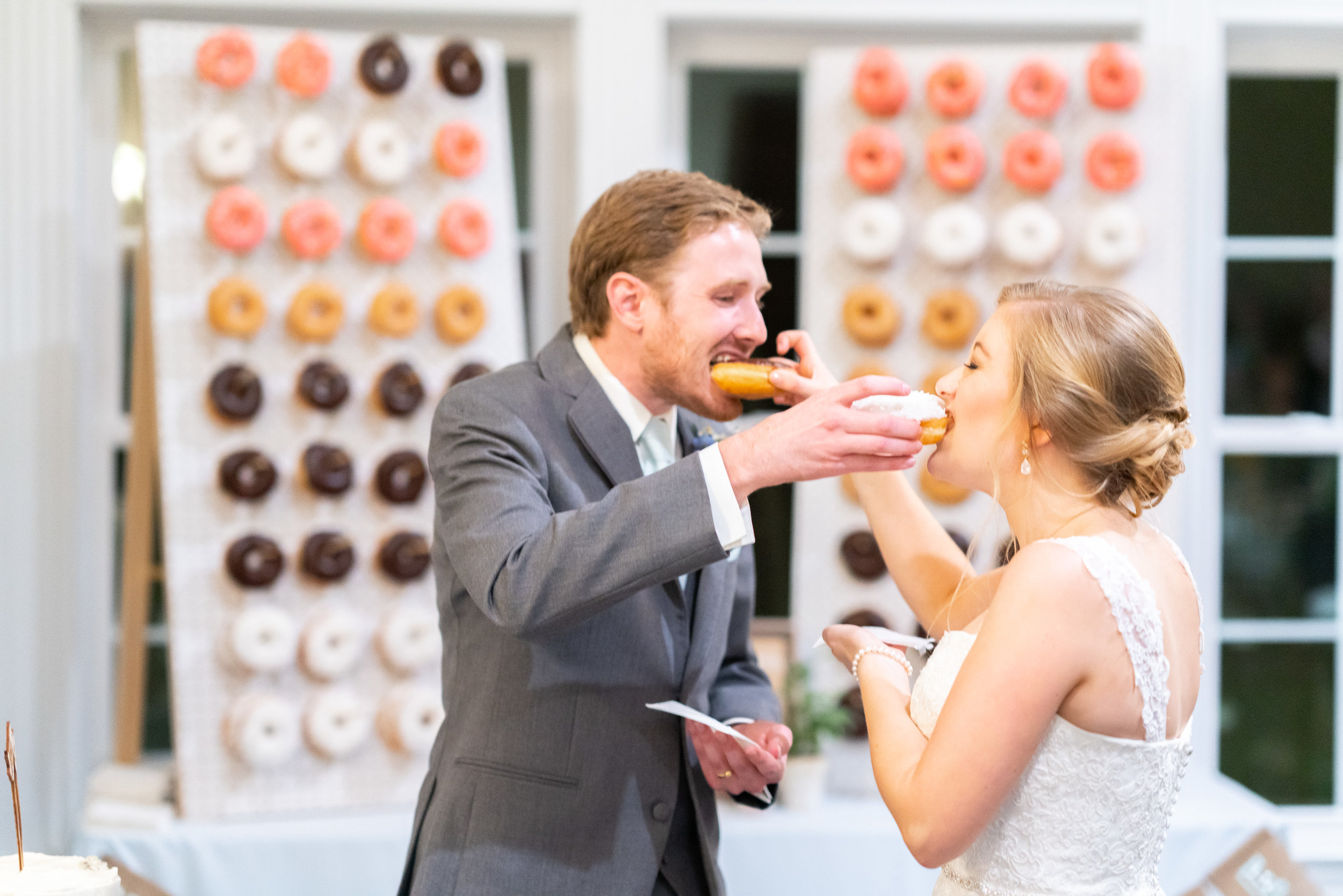 Bride and groom sharing donuts during cake cutting at stone manor country club