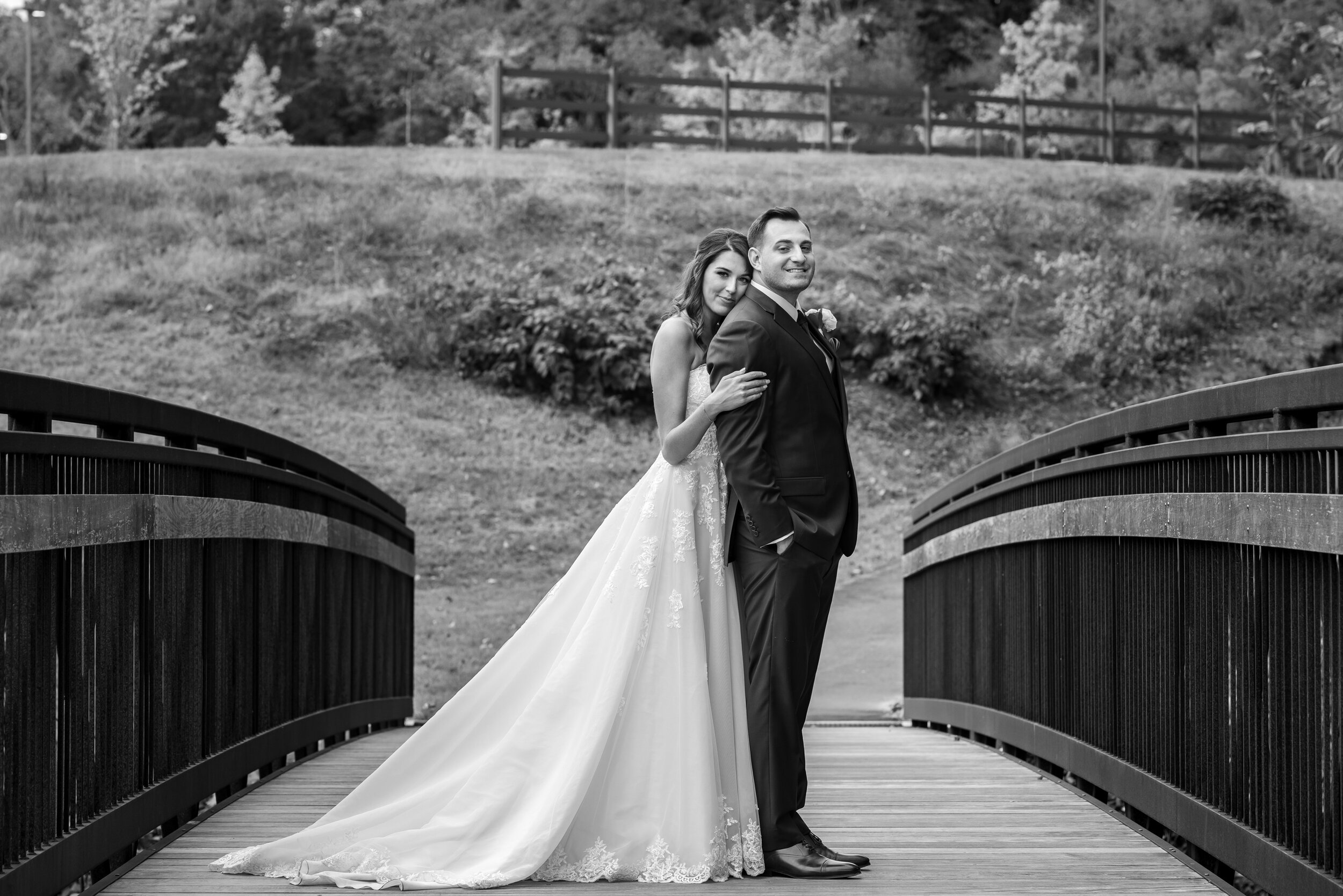 Bride snuggling groom on the bridge behind Riverview at Occoquan