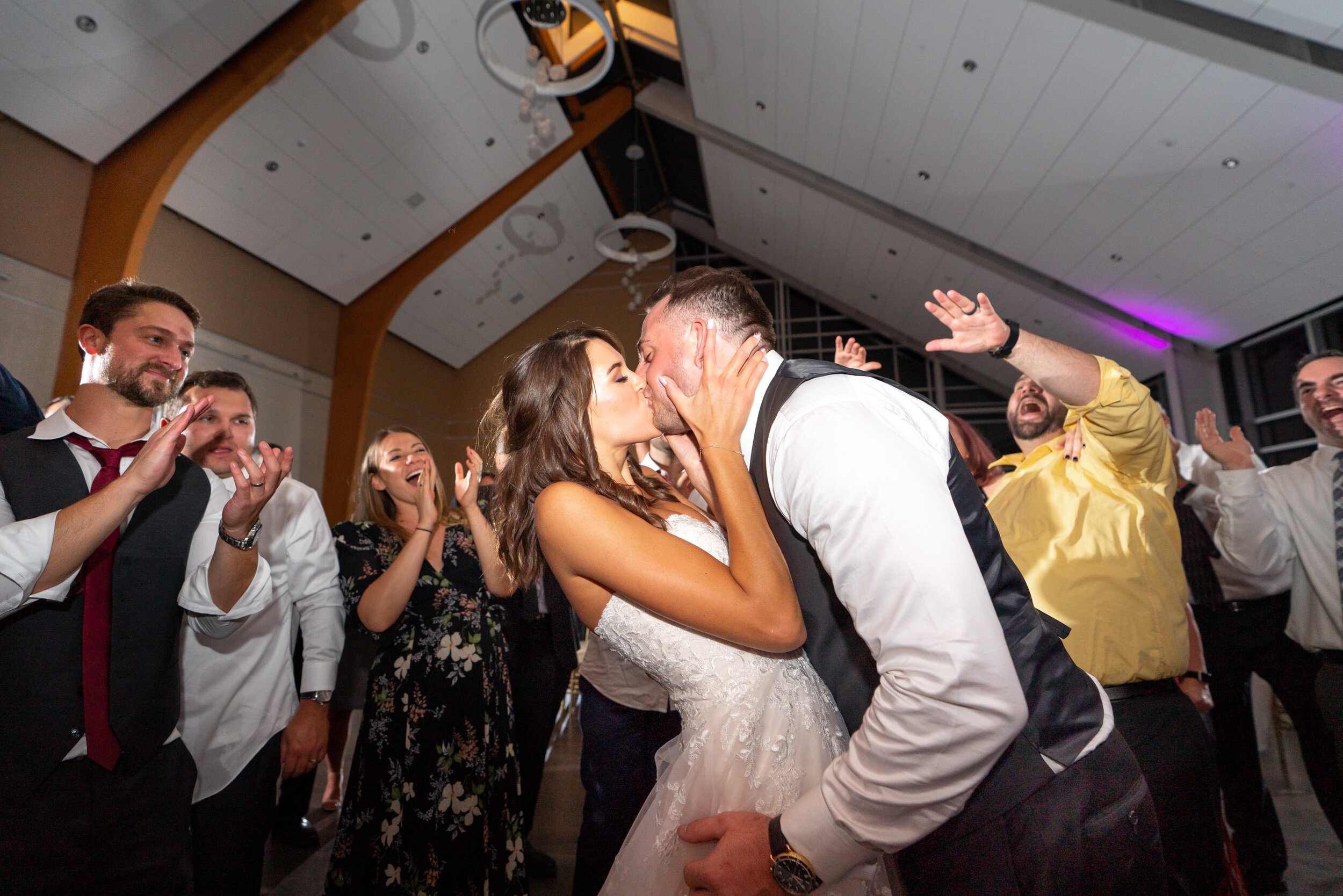 Bride and groom kissing in the circle of their friends during the last song